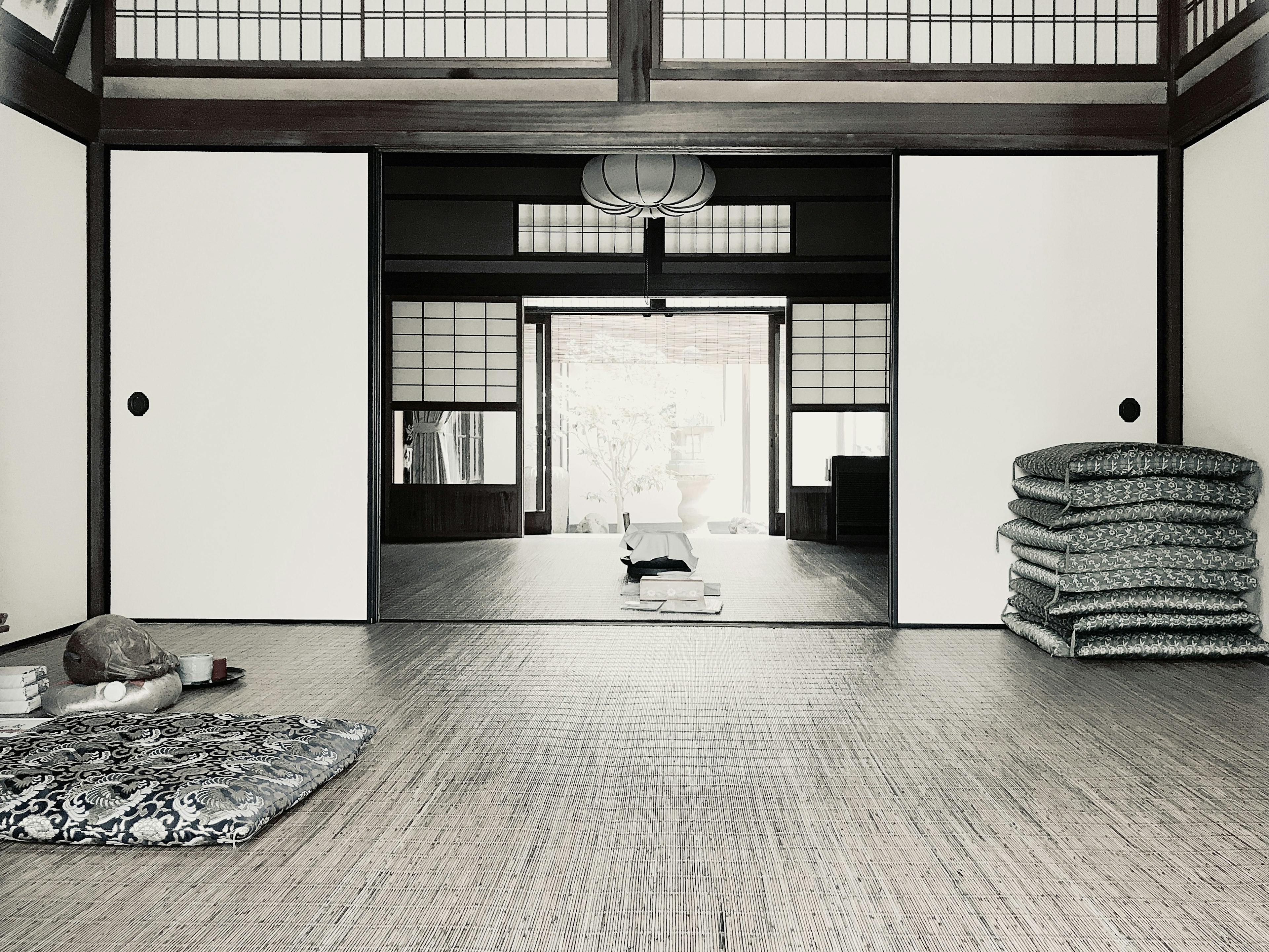 Simple interior of a Japanese room featuring sliding doors tatami mats and stacked bedding on the right