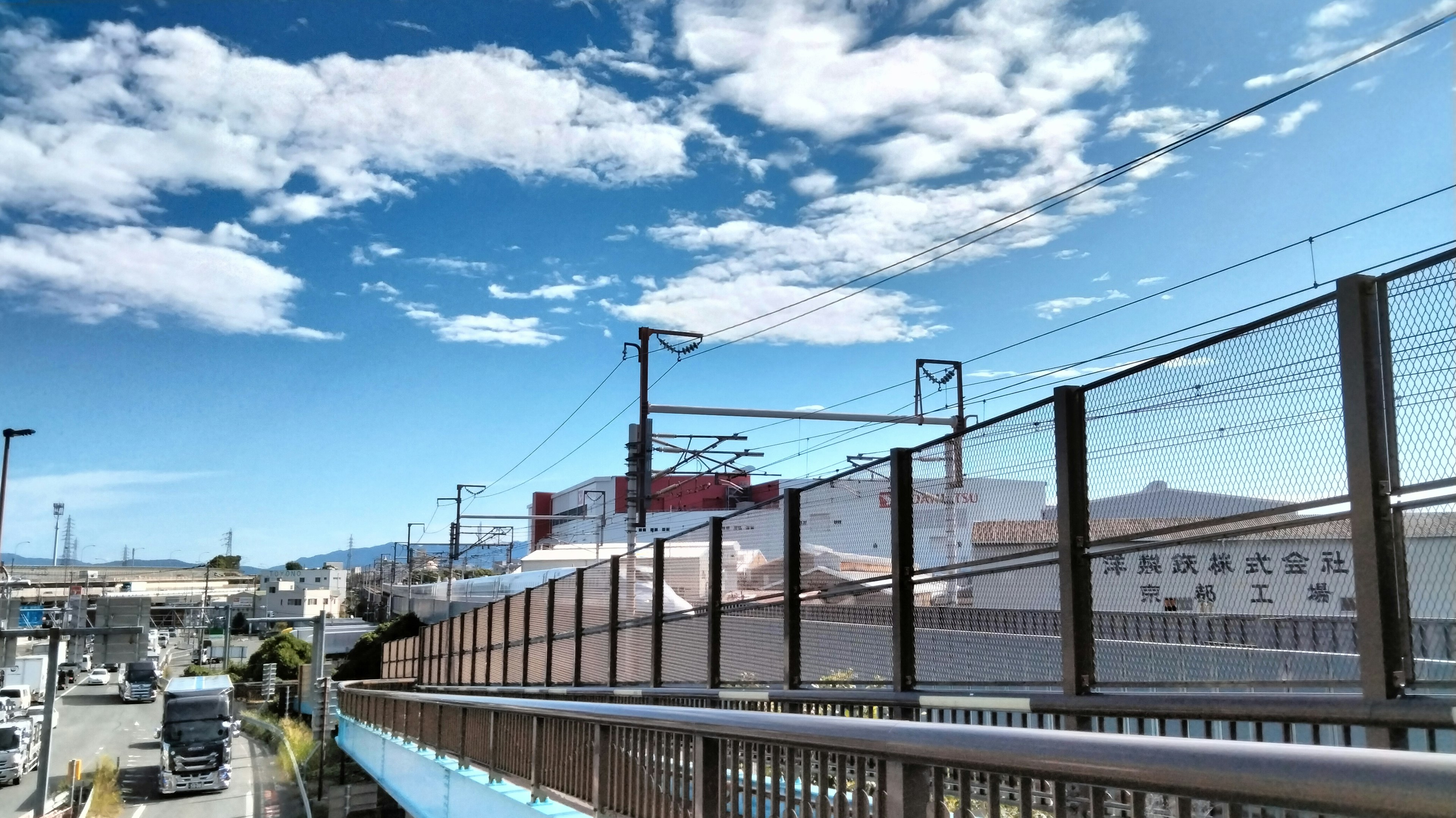 Paisaje con cielo azul y nubes blancas que presenta ferrocarriles y edificios