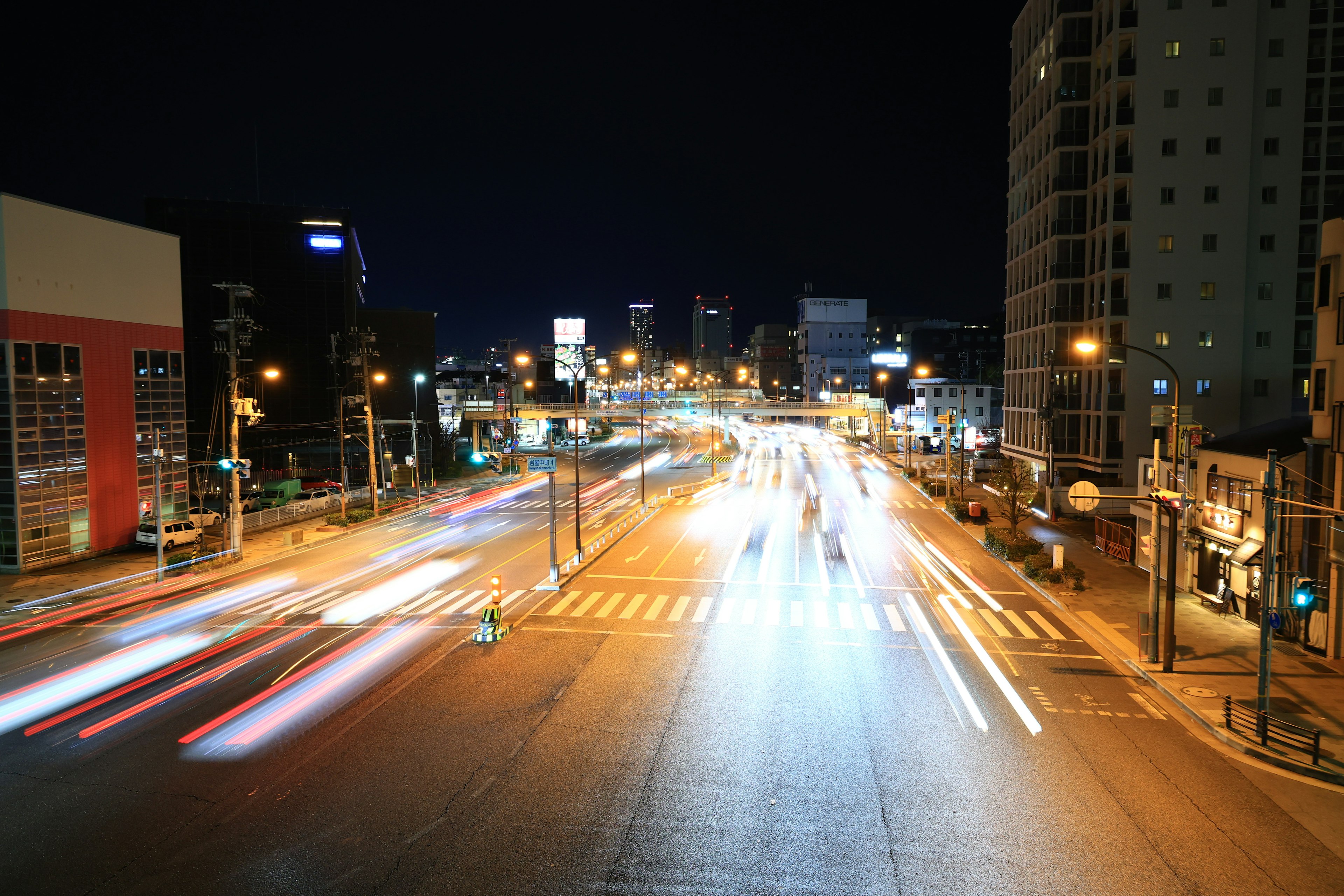 Traînées de lumière des véhicules traversant une intersection urbaine la nuit