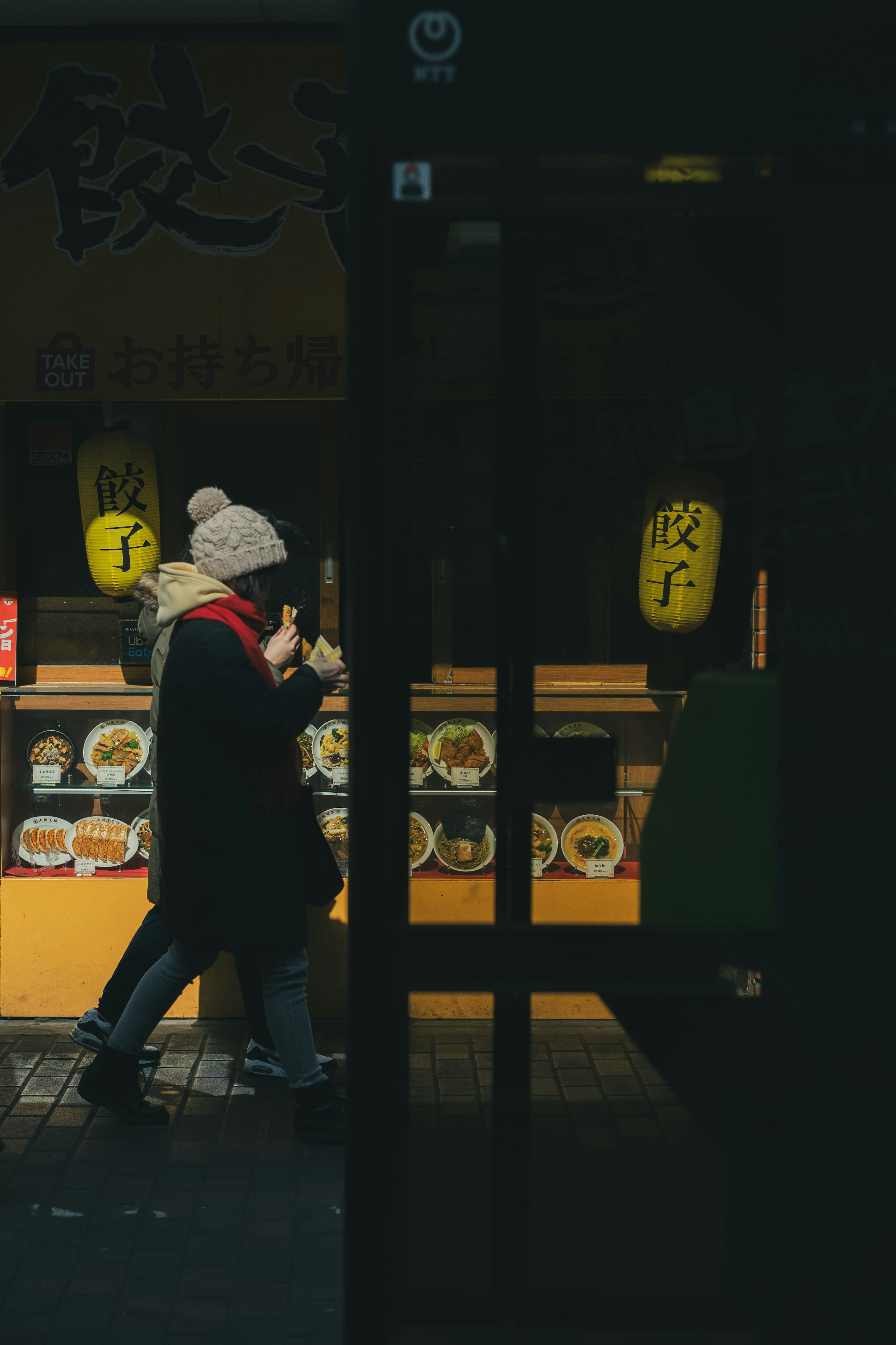 Pareja caminando frente a una tienda poco iluminada con letreros brillantes