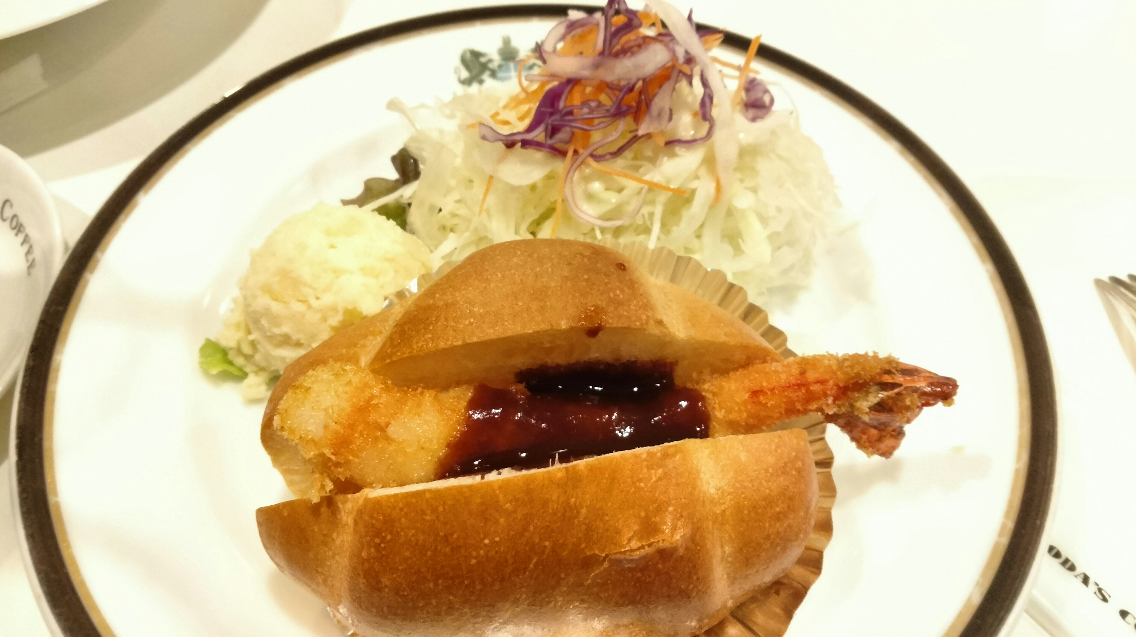 Plate featuring a shrimp sandwich with sauce and a side salad