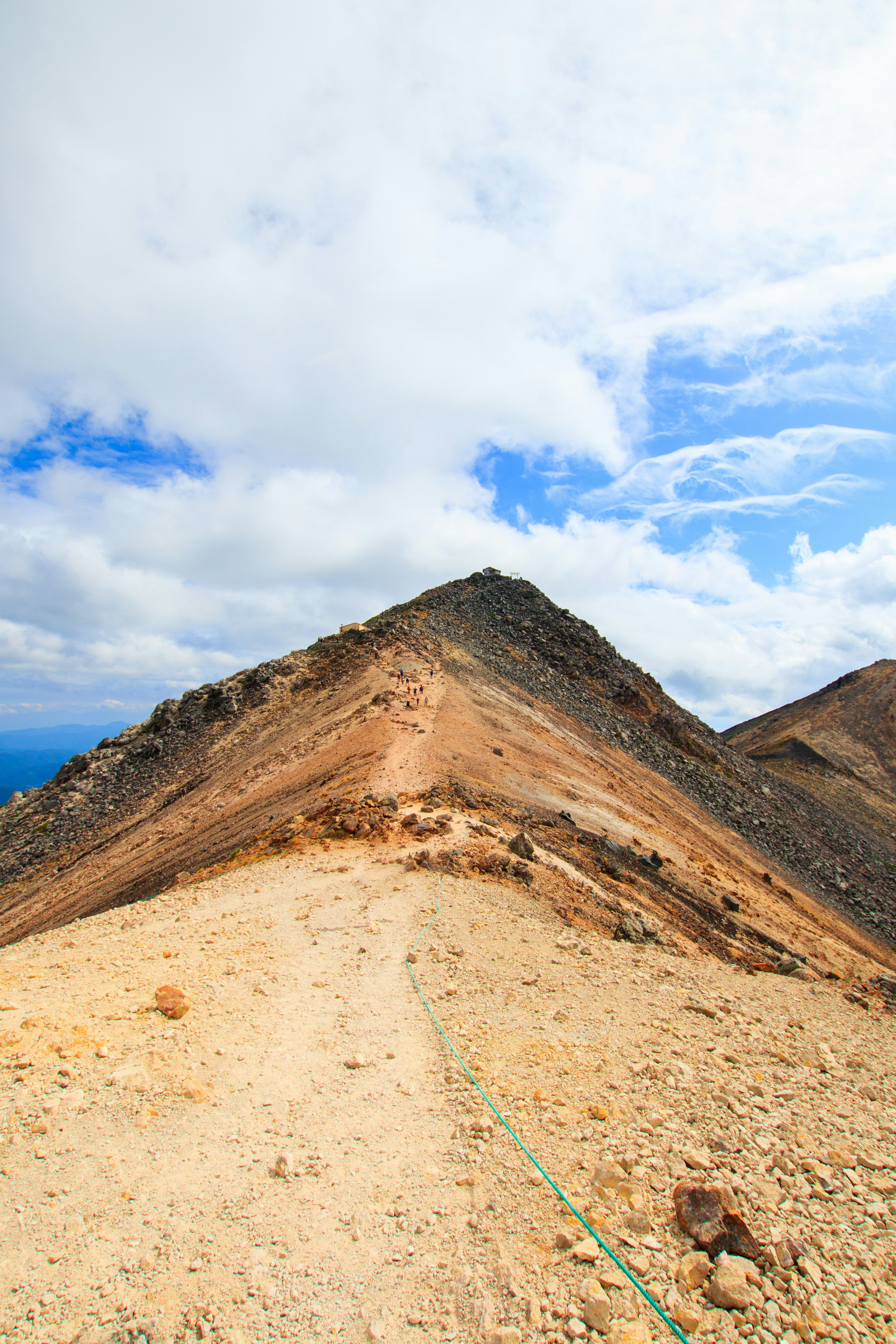 Un camino que lleva a la cima de una montaña bajo un cielo azul con nubes