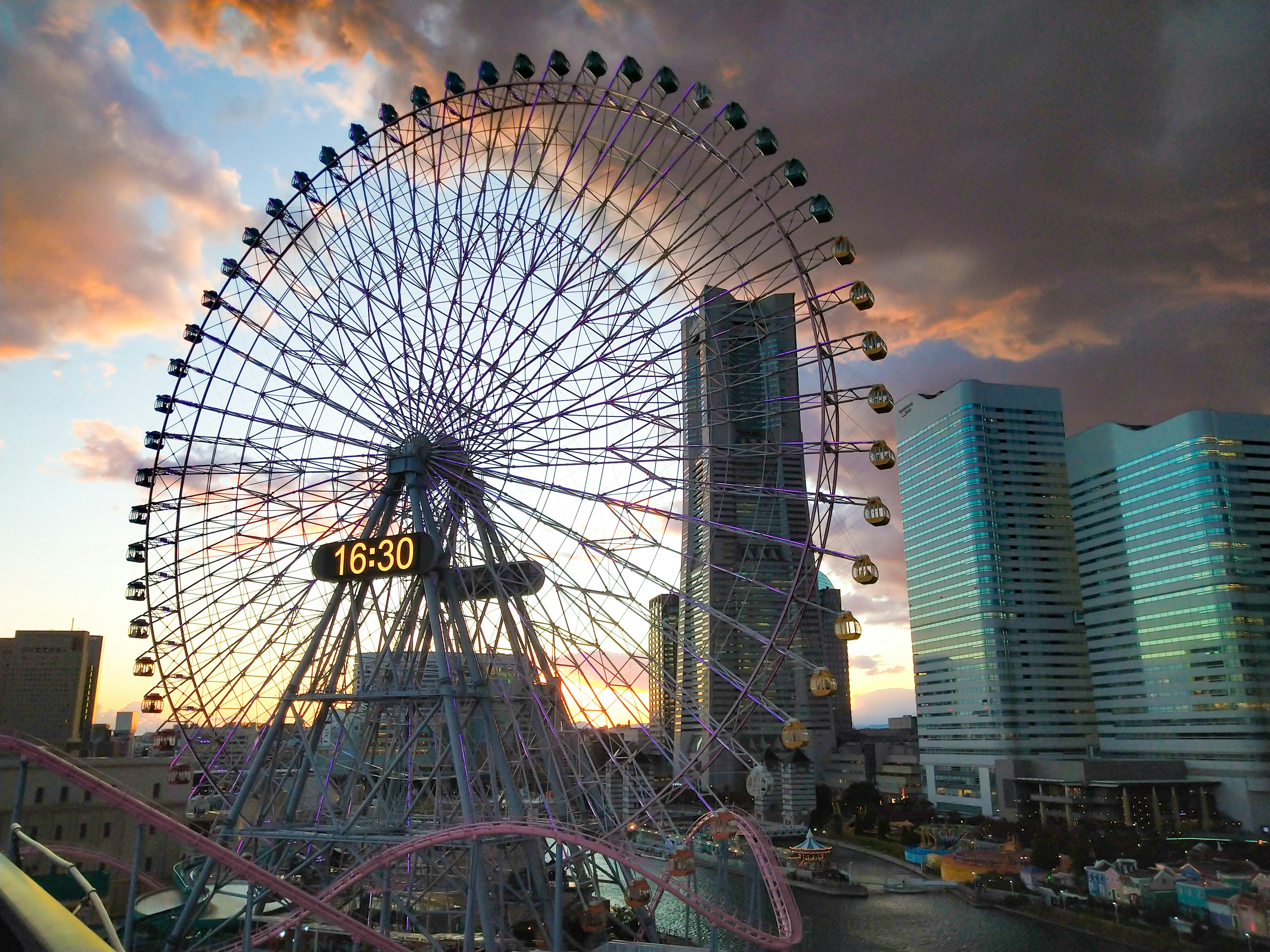 Grande roue avec un magnifique ciel de coucher de soleil et des gratte-ciels modernes en arrière-plan