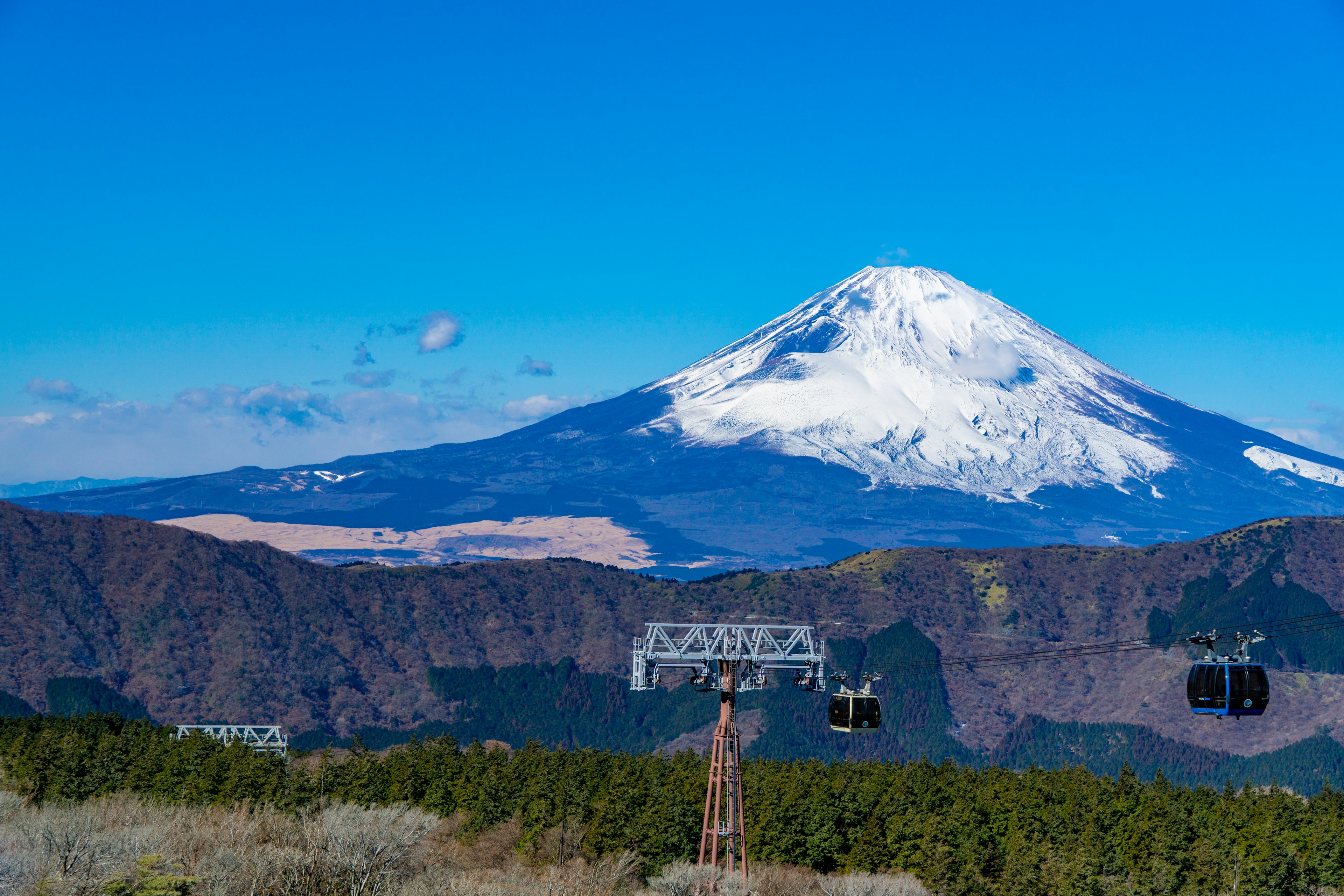 富士山在晴朗的蓝天下耸立，雪顶和周围山脉