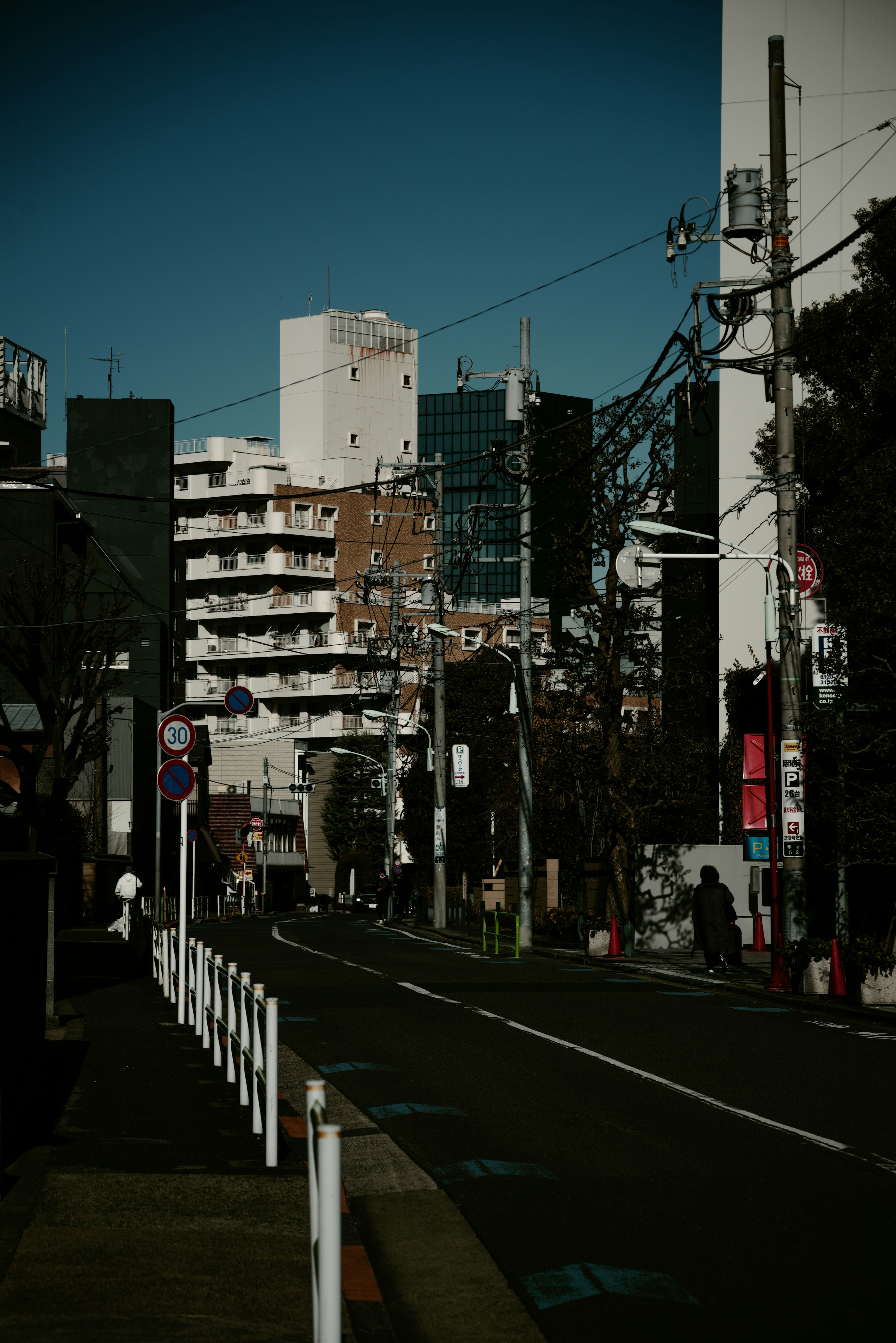 Tokyo cityscape featuring buildings, clear blue sky, street and lamp posts, power lines, urban scenery