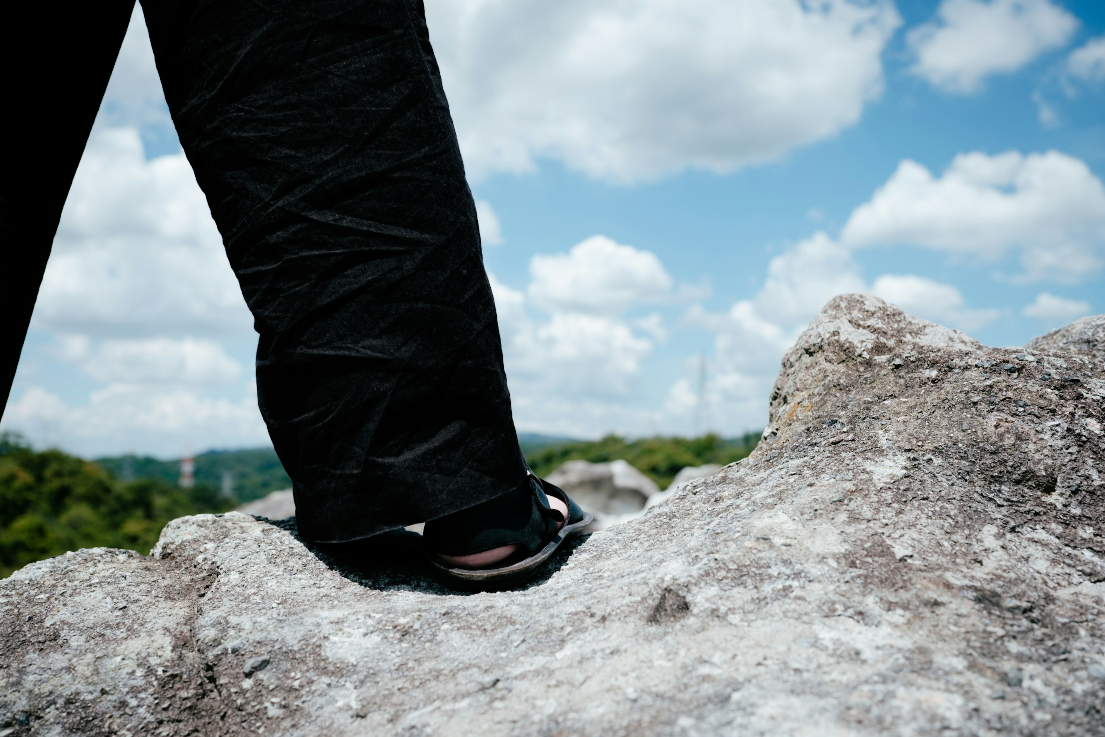 Kaki dalam celana hitam berdiri di atas batu