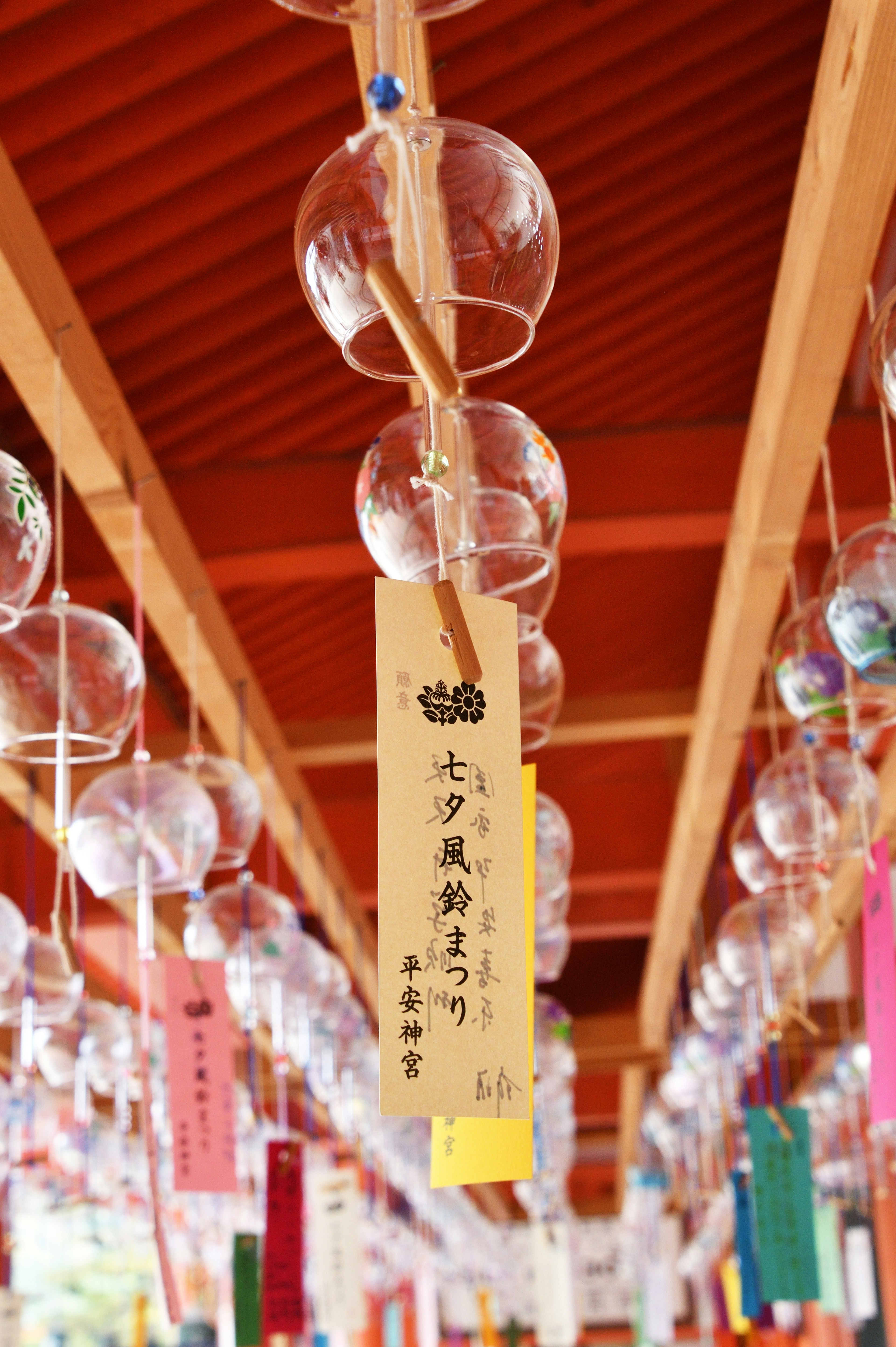 风铃悬挂在红色屋顶下，带有彩色标签