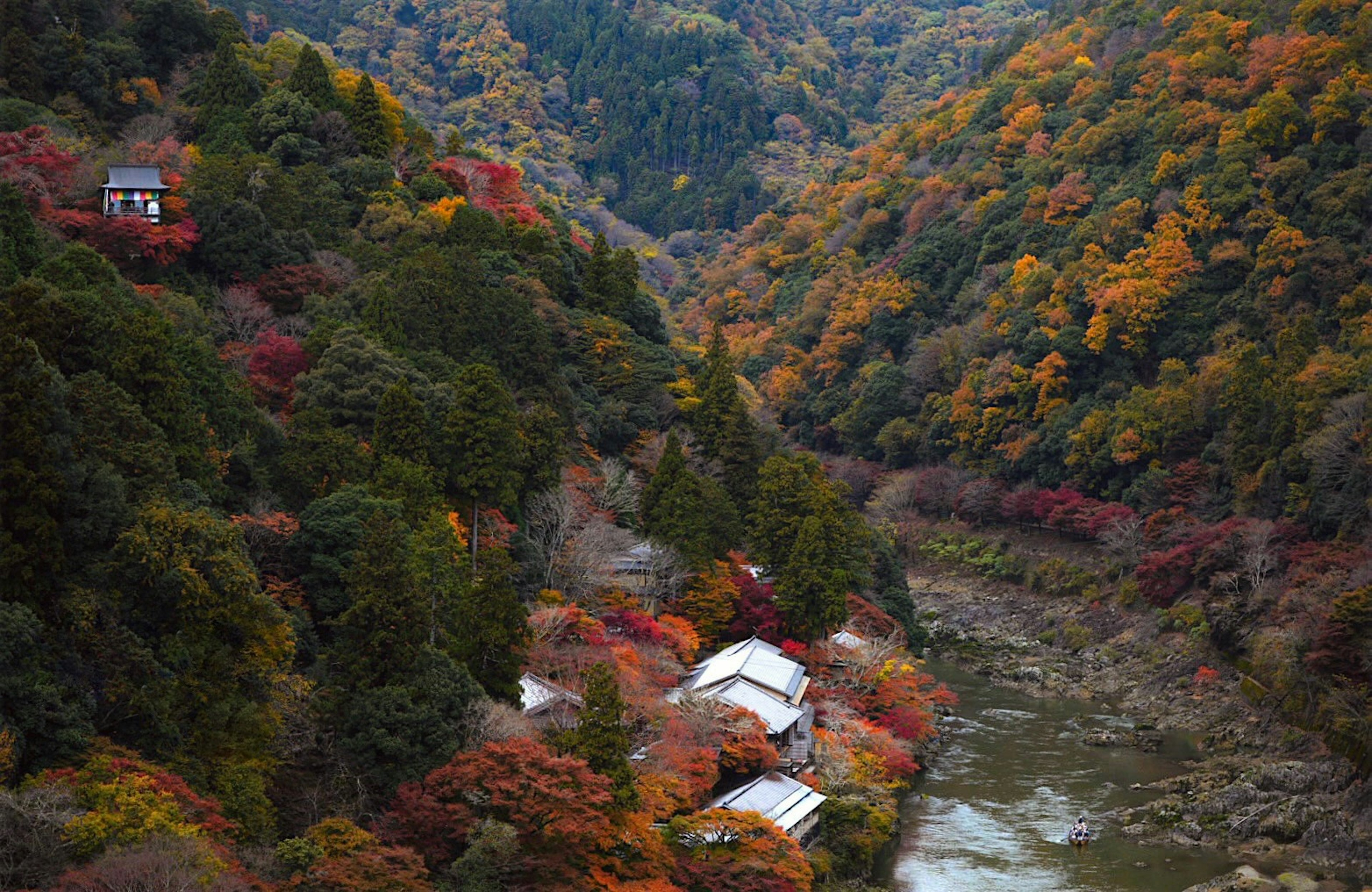 ทิวทัศน์ที่สวยงามของภูเขาสีฤดูใบไม้ร่วงและแม่น้ำที่มีบ้านเล็กๆ กระจัดกระจาย