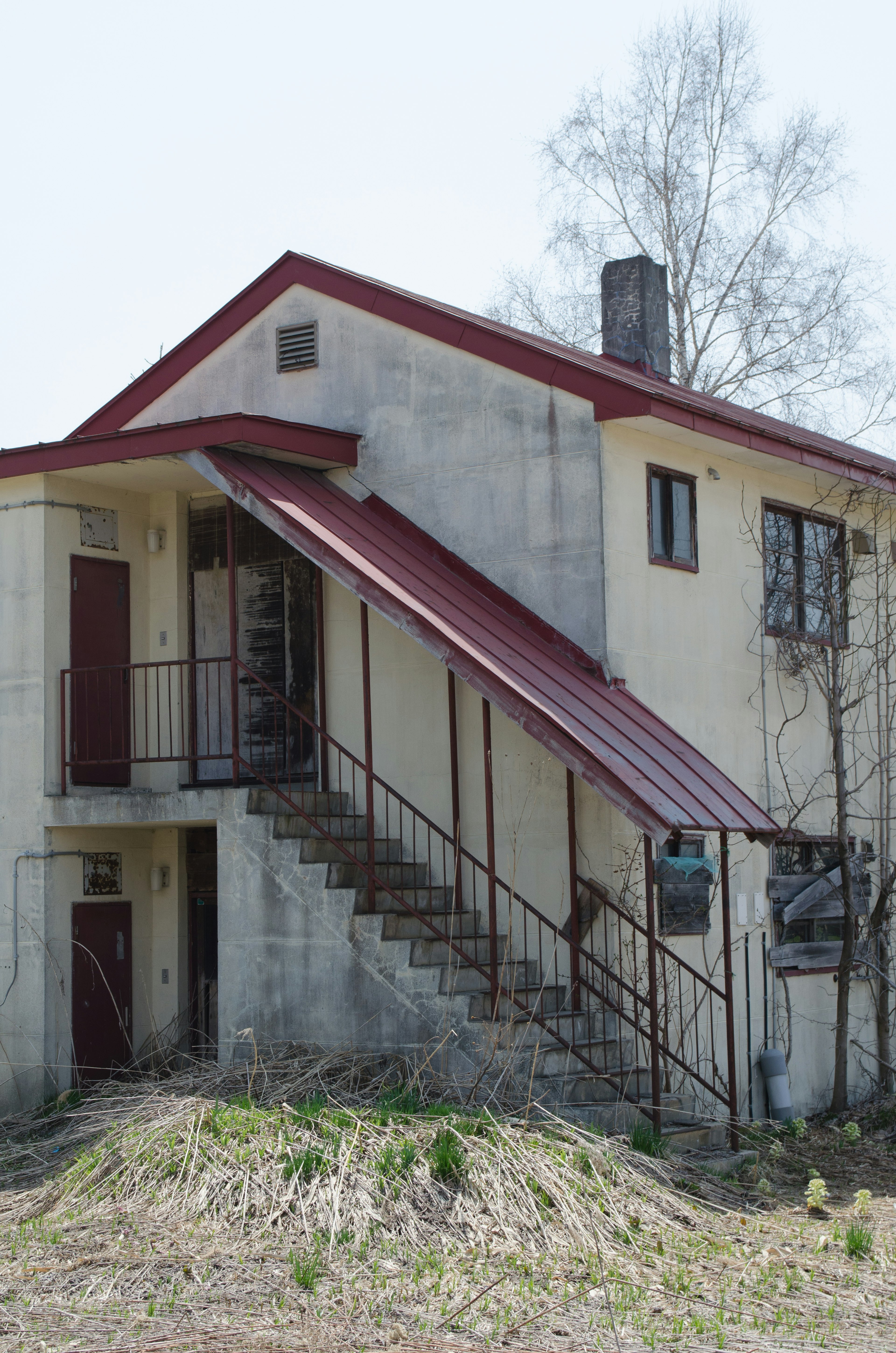 Extérieur d'une maison à deux étages avec un toit rouge comportant des escaliers et des rampes en métal