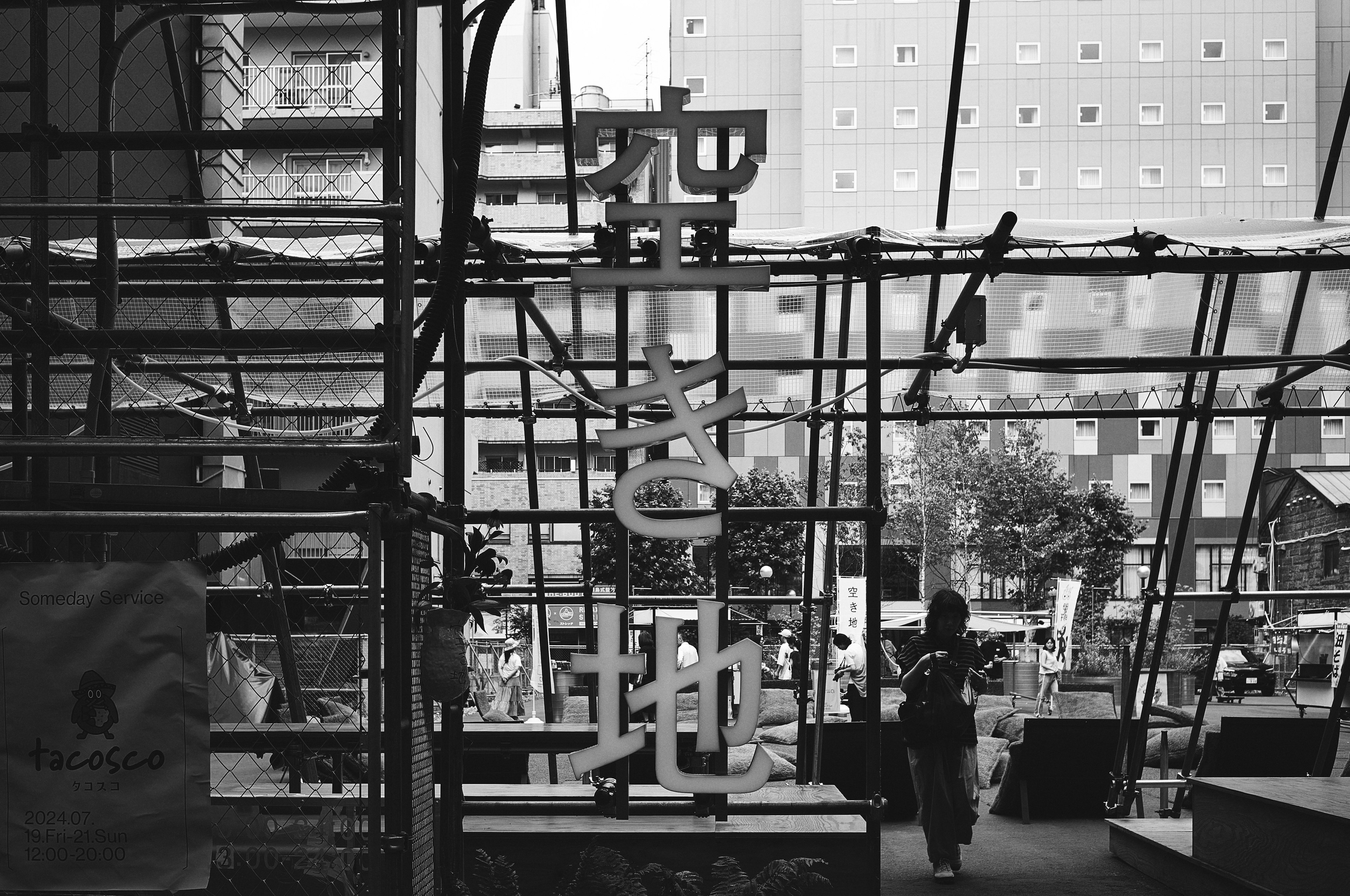 Scène en noir et blanc avec des structures urbaines et des échafaudages de construction