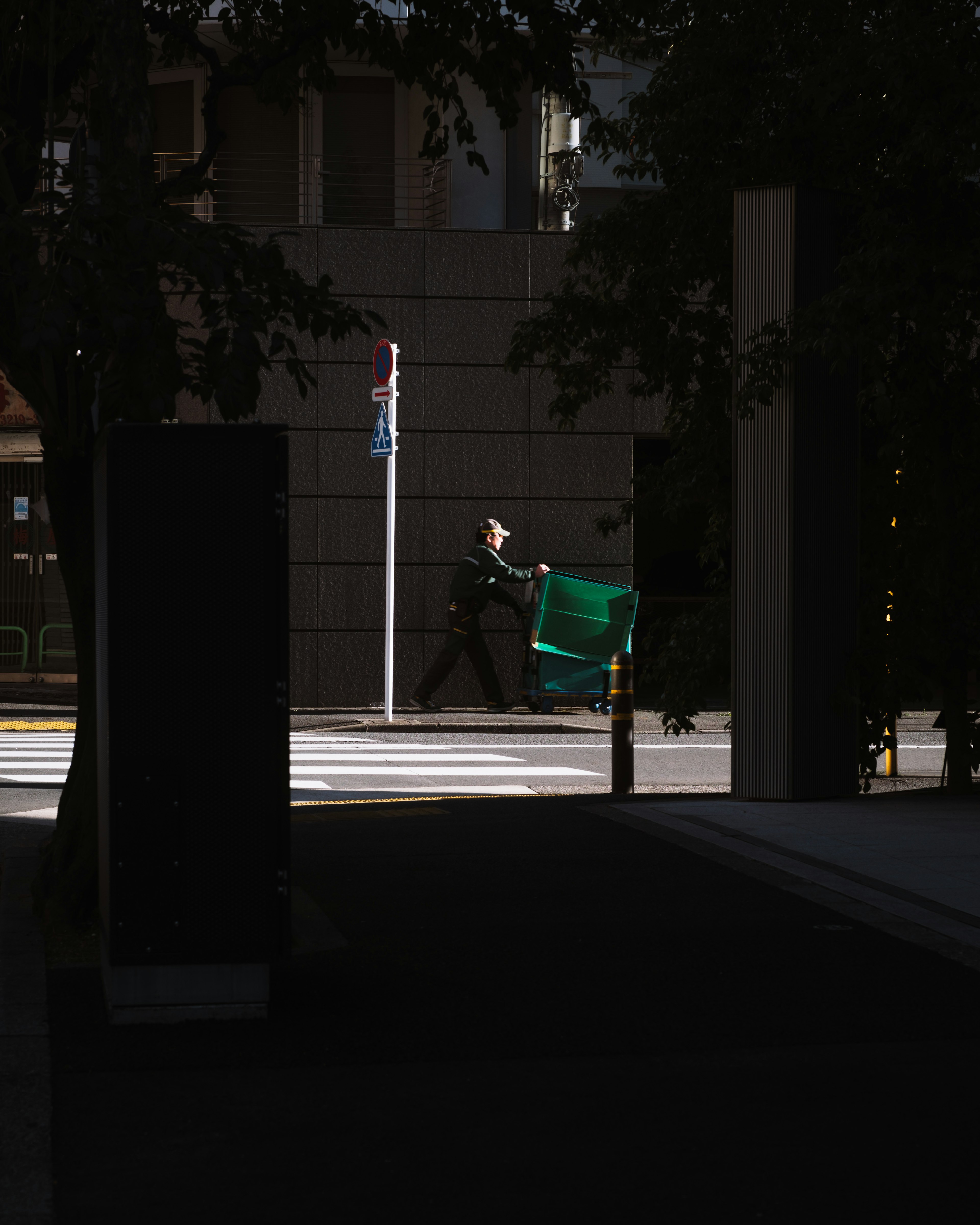 Silhouette of a person carrying a green chair against a dark background