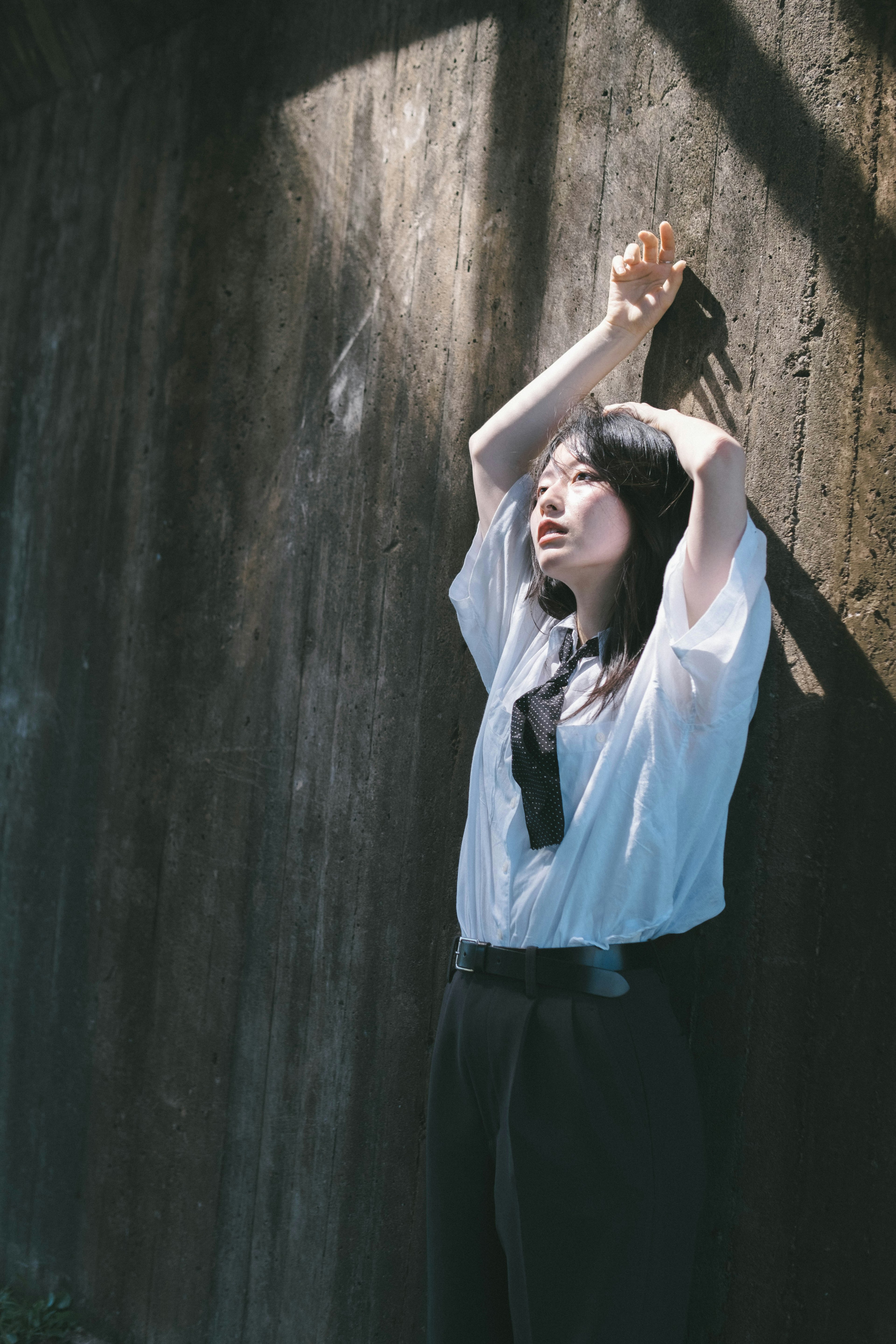 A woman leaning against a wall with her hands raised