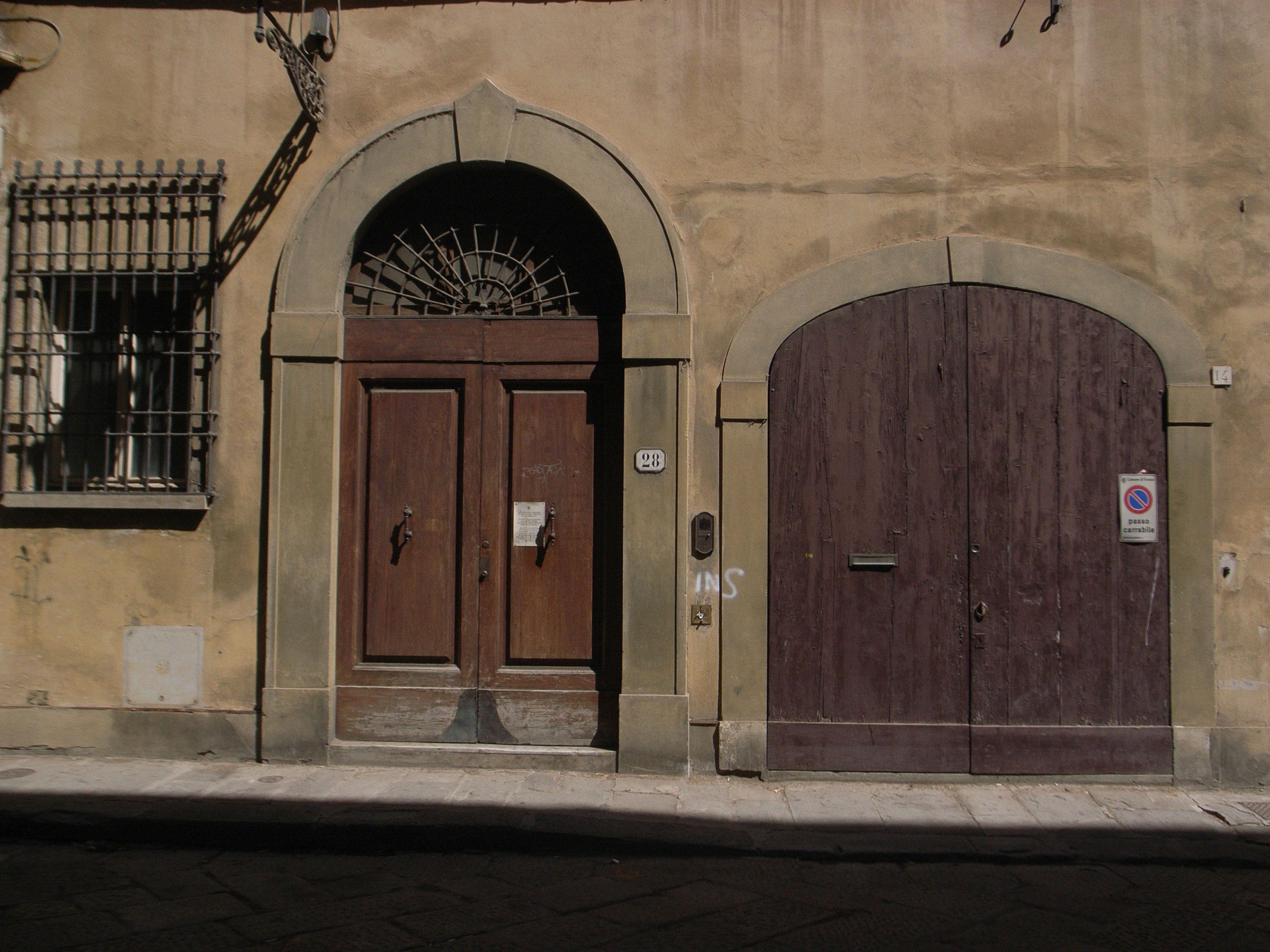 Two wooden doors and an arched window on the exterior of an old building