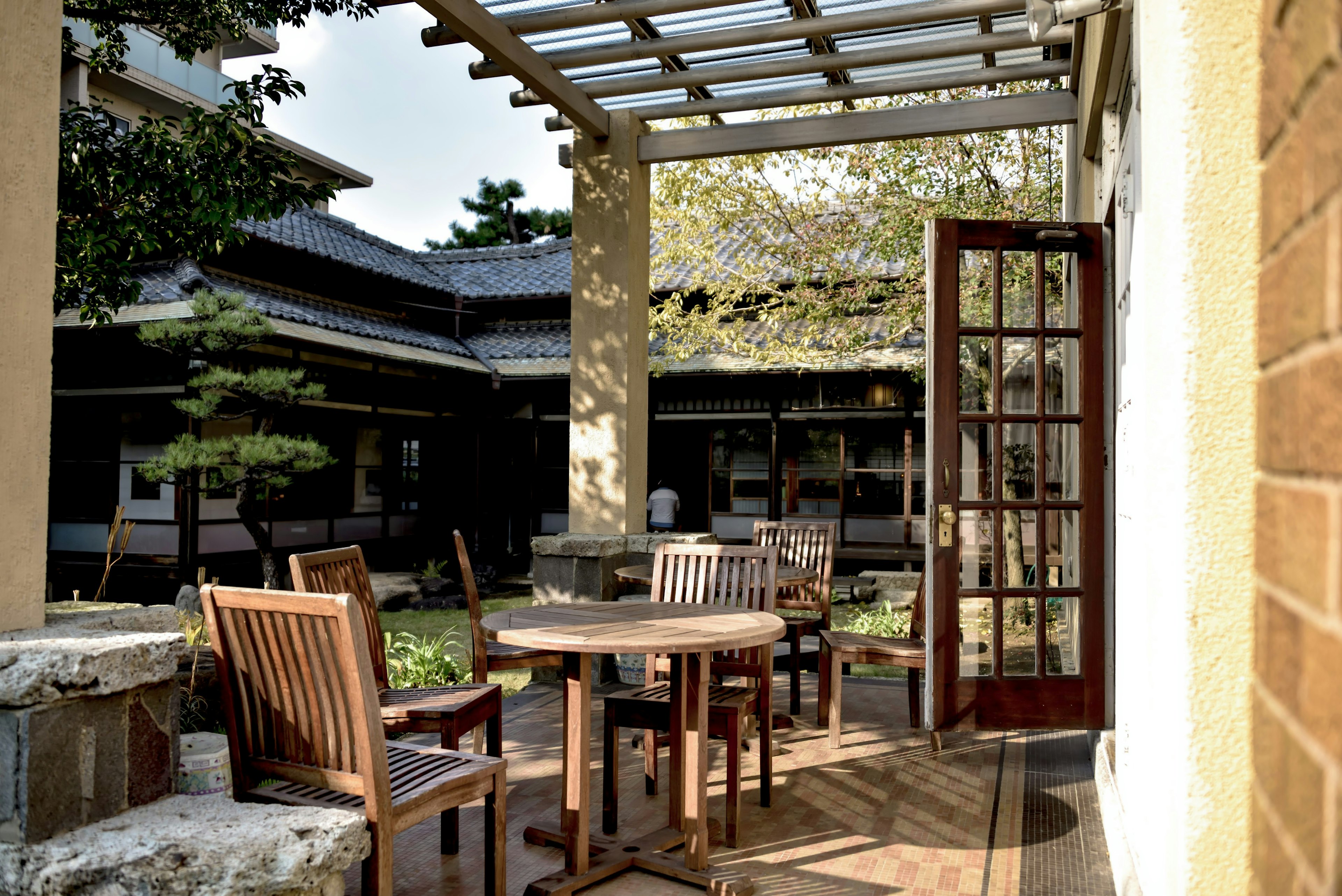 Wooden tables and chairs arranged on a serene terrace overlooking a garden