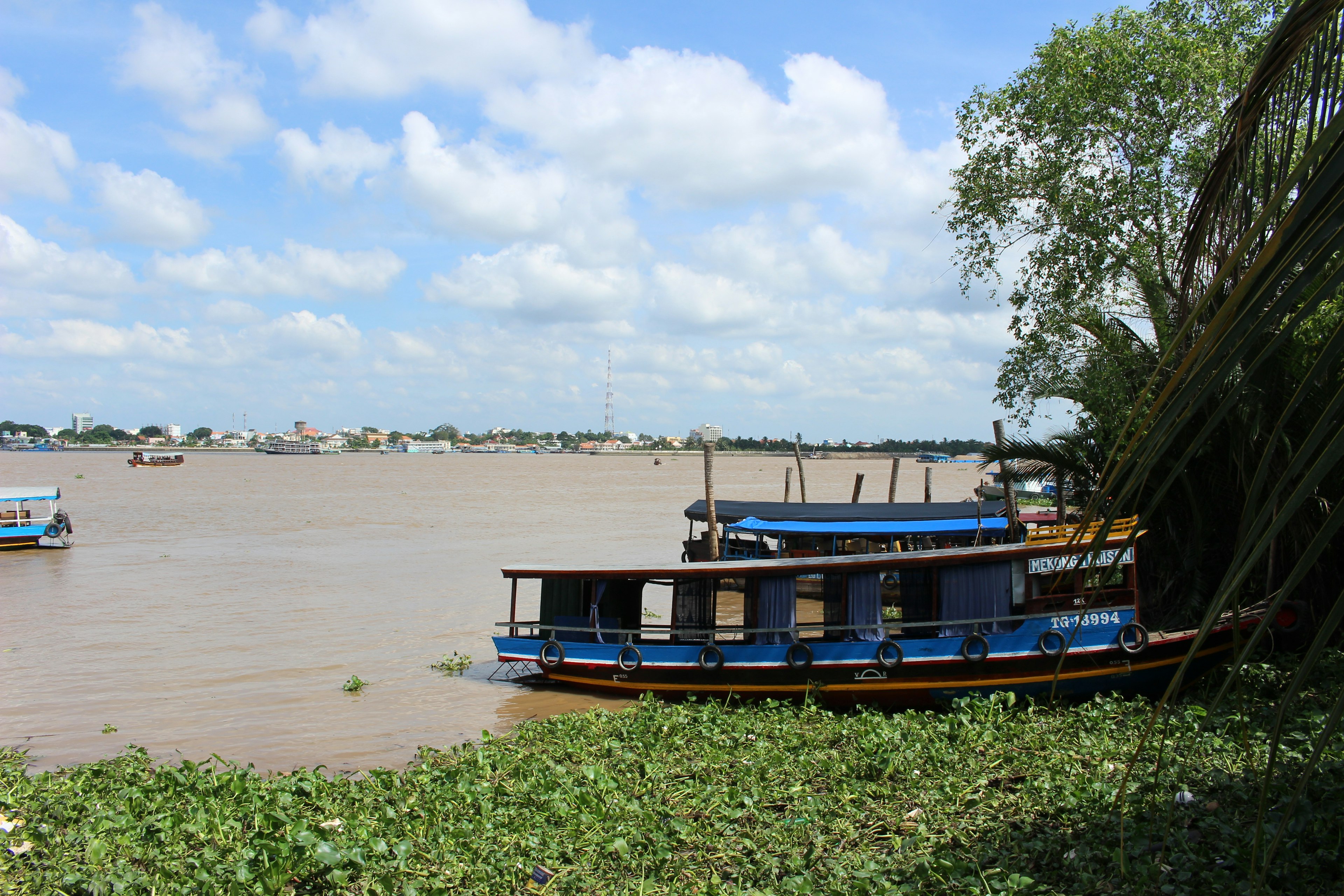 Blue boats docked by the river under a blue sky