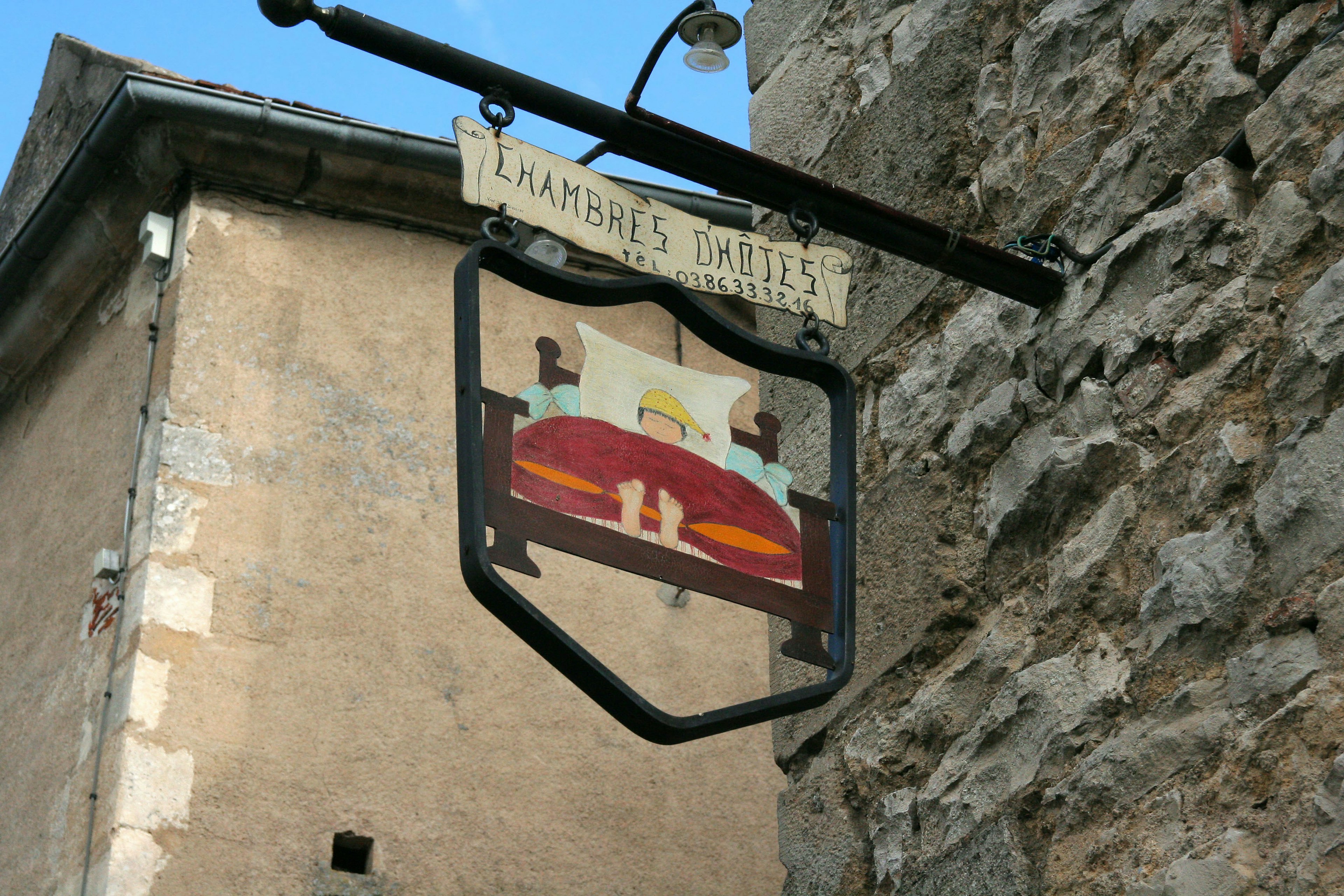 Sign of an inn featuring an illustration of a person sleeping in a bed