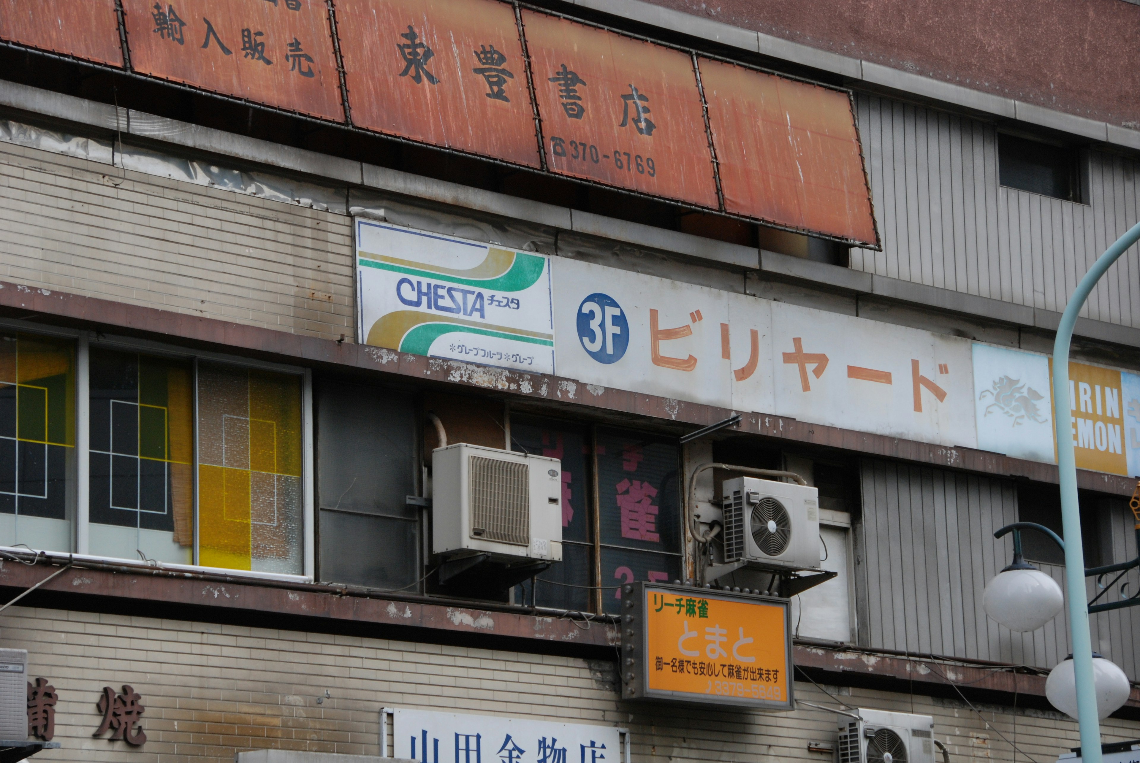 Extérieur d'un vieux bâtiment avec des panneaux d'affichage et des unités de climatisation