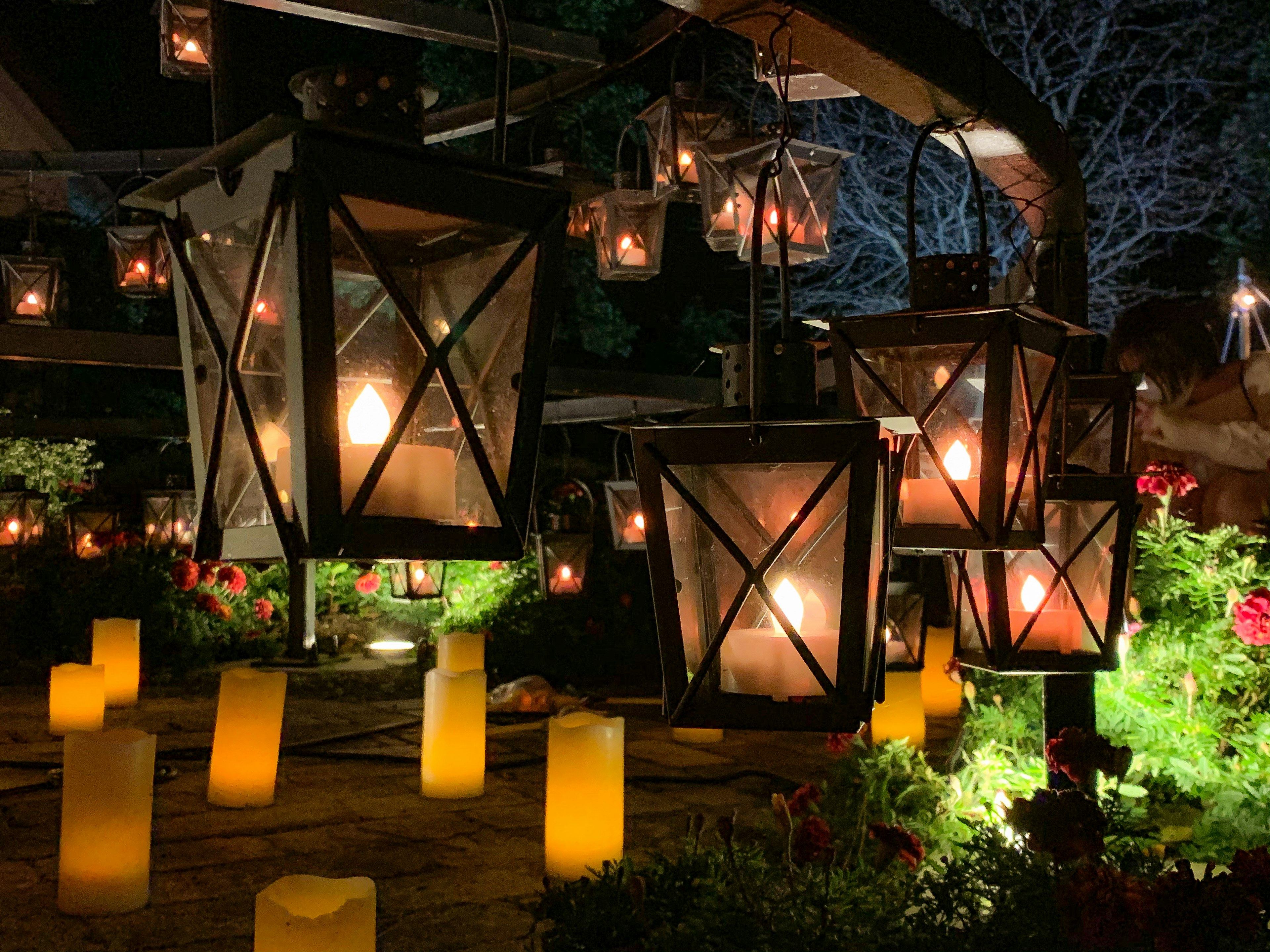 Linternas colgantes y suave luz de velas en un jardín nocturno