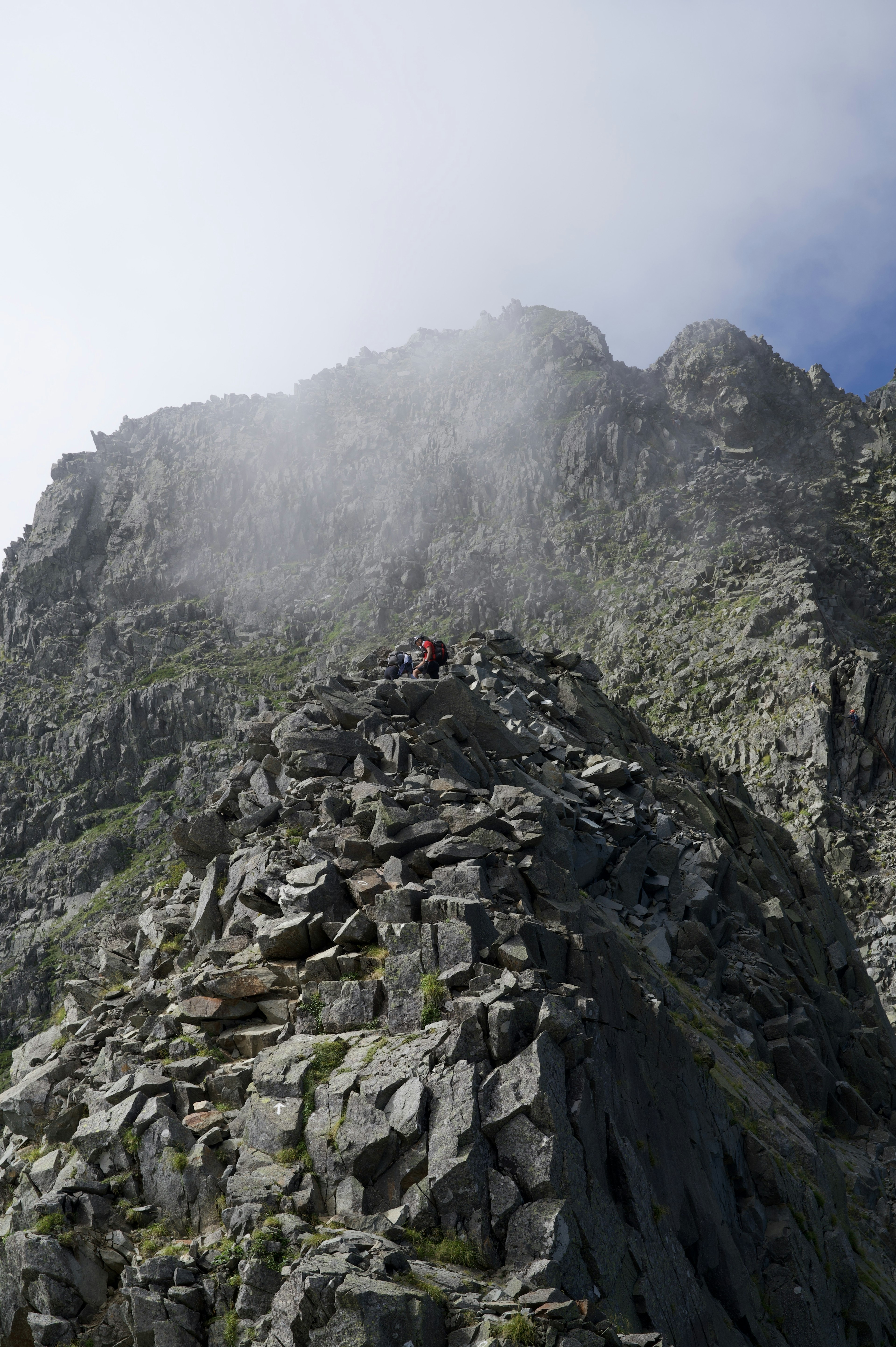 Grimpeur montant un sommet rocheux enveloppé de brume