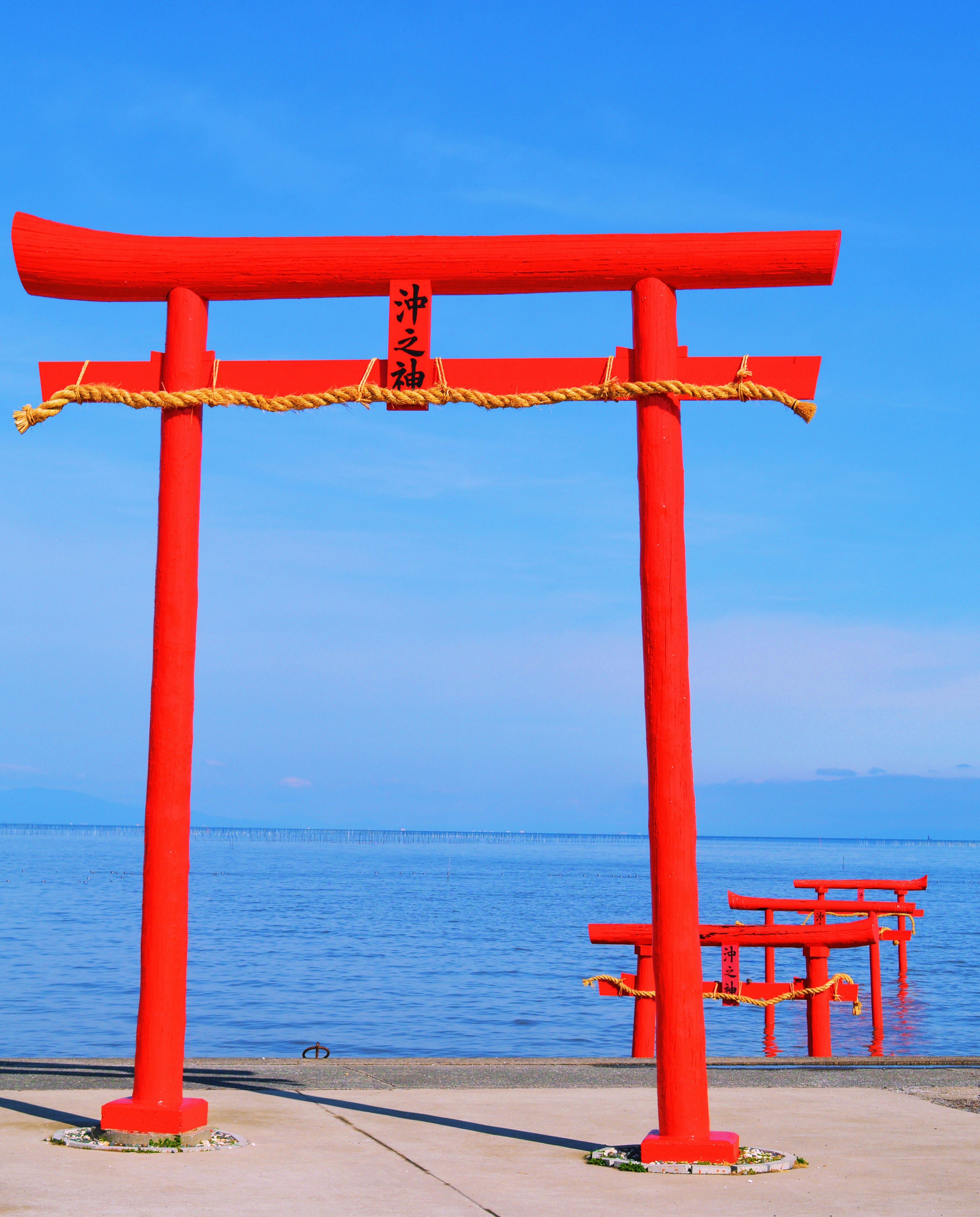 Red torii gate against a blue sky and ocean