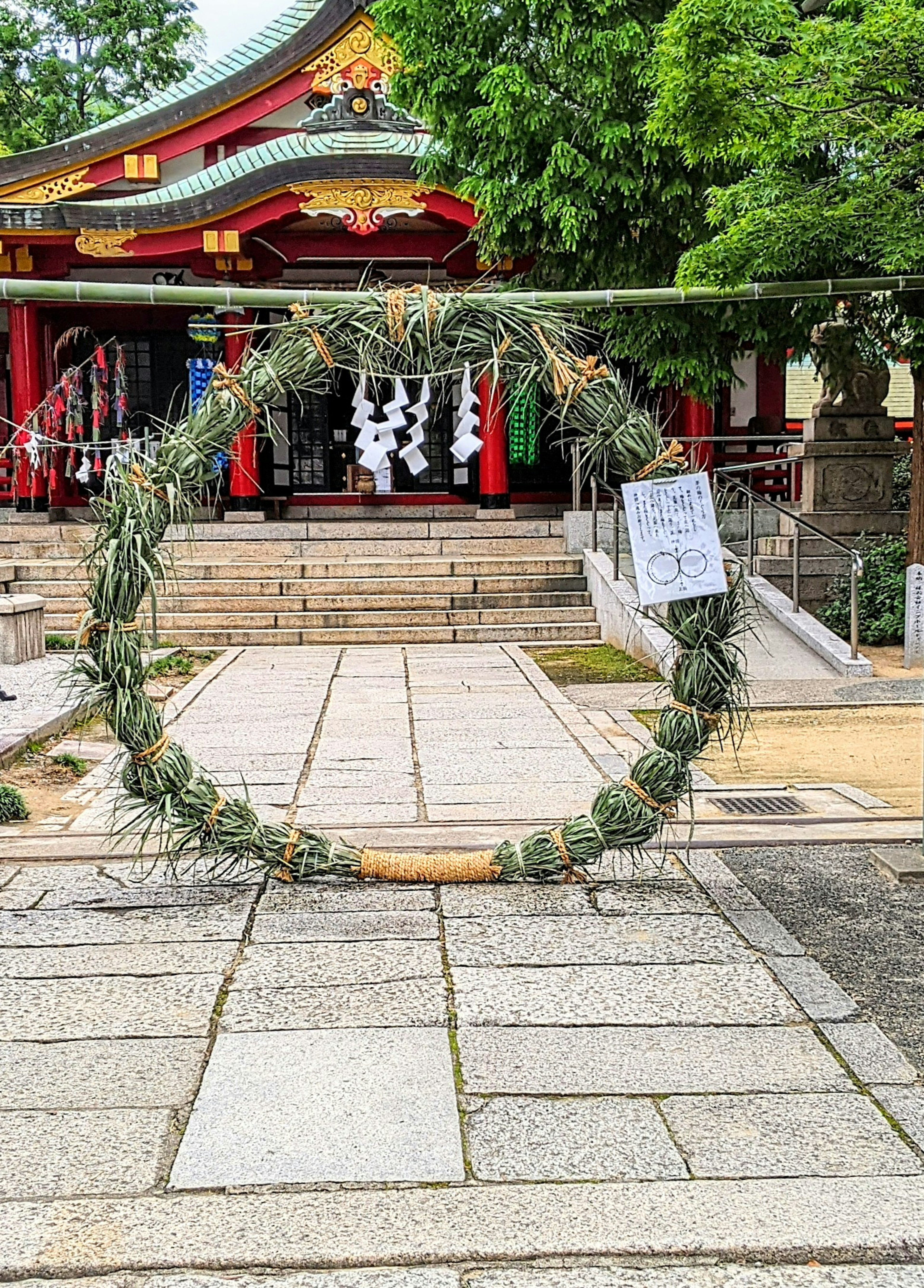 Green ceremonial wreath in front of a shrine with stone pavement