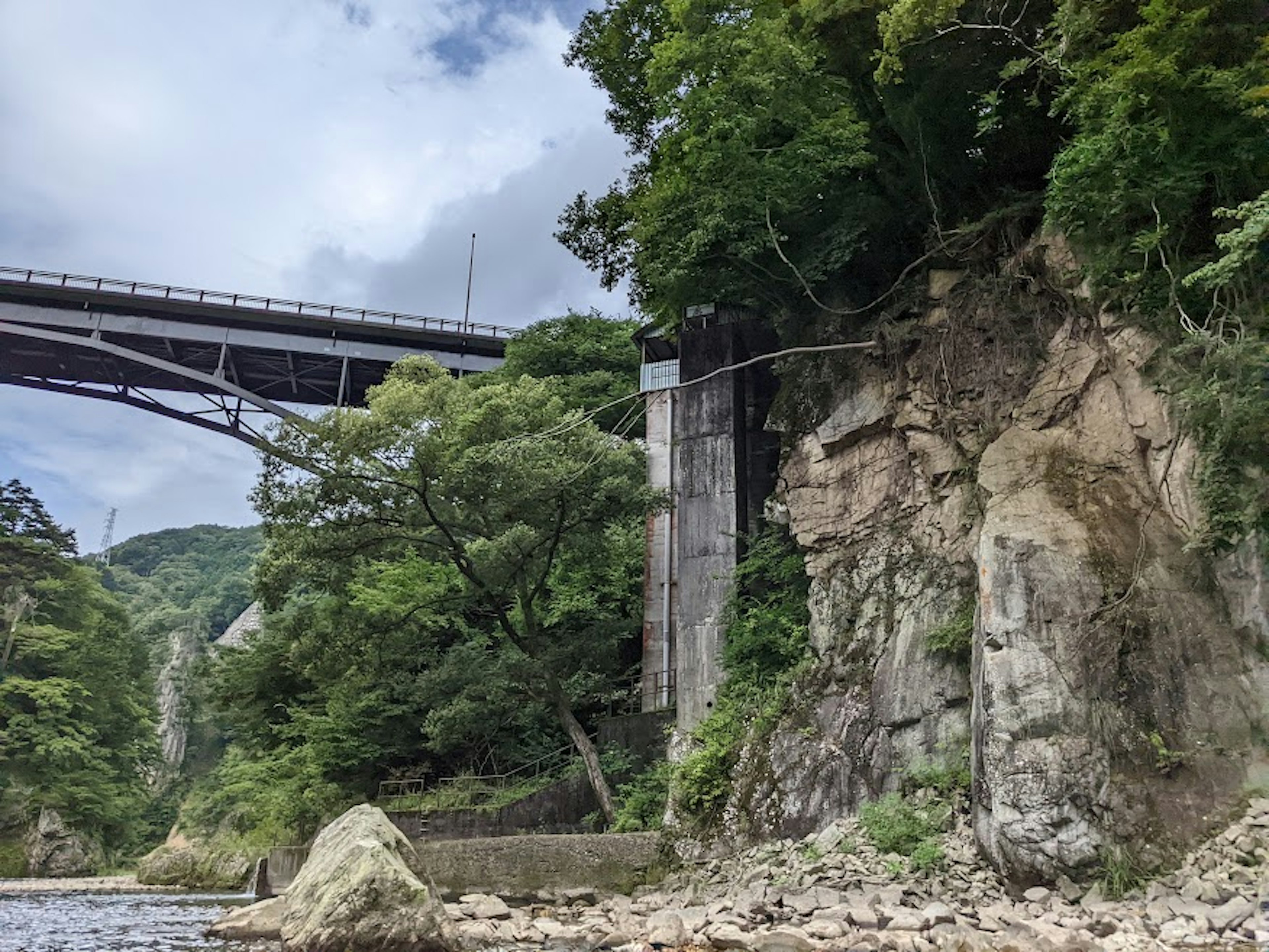 河流上方的桥梁与岩石悬崖和茂密绿树的风景