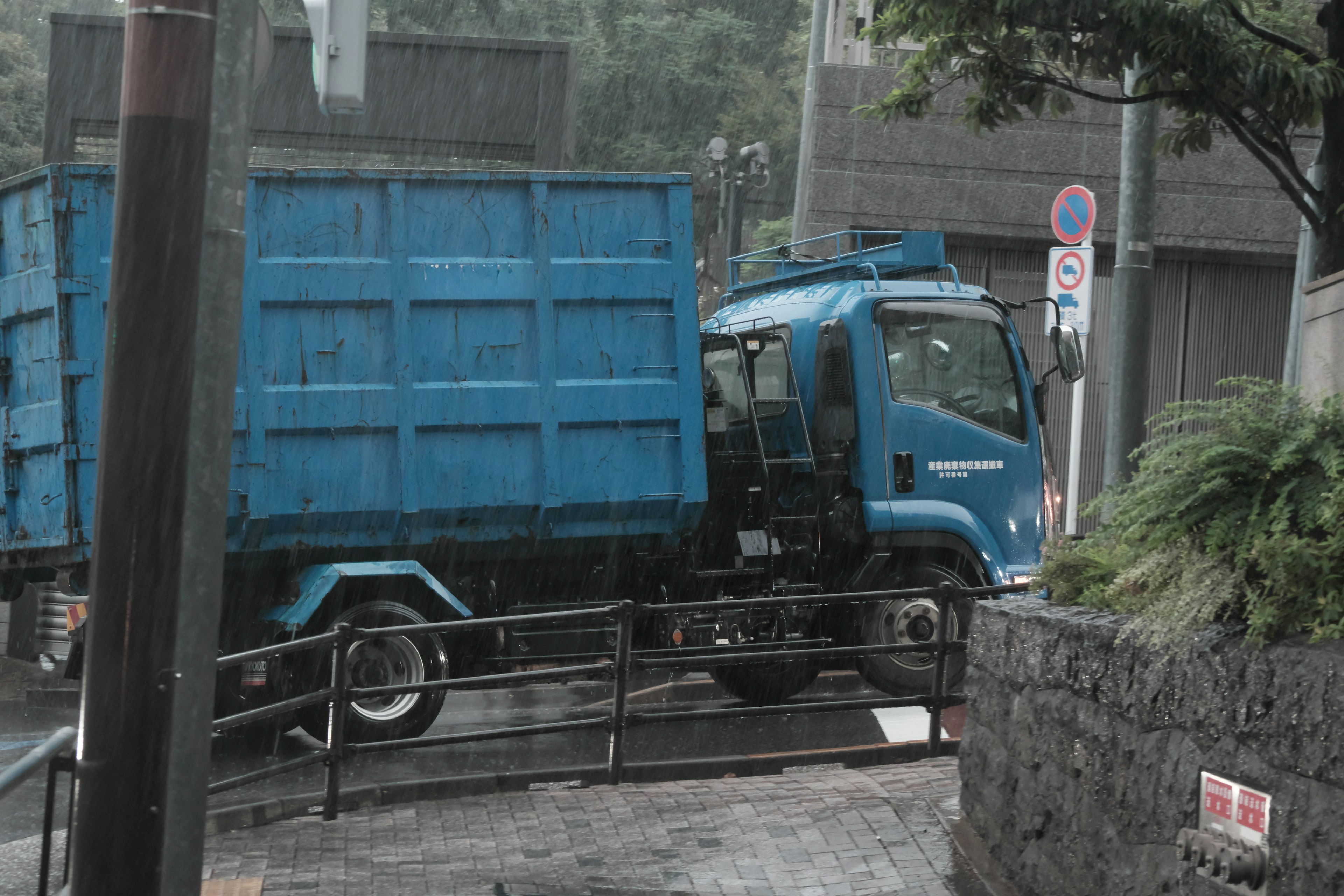 Camion bleu tournant à un coin sous une forte pluie