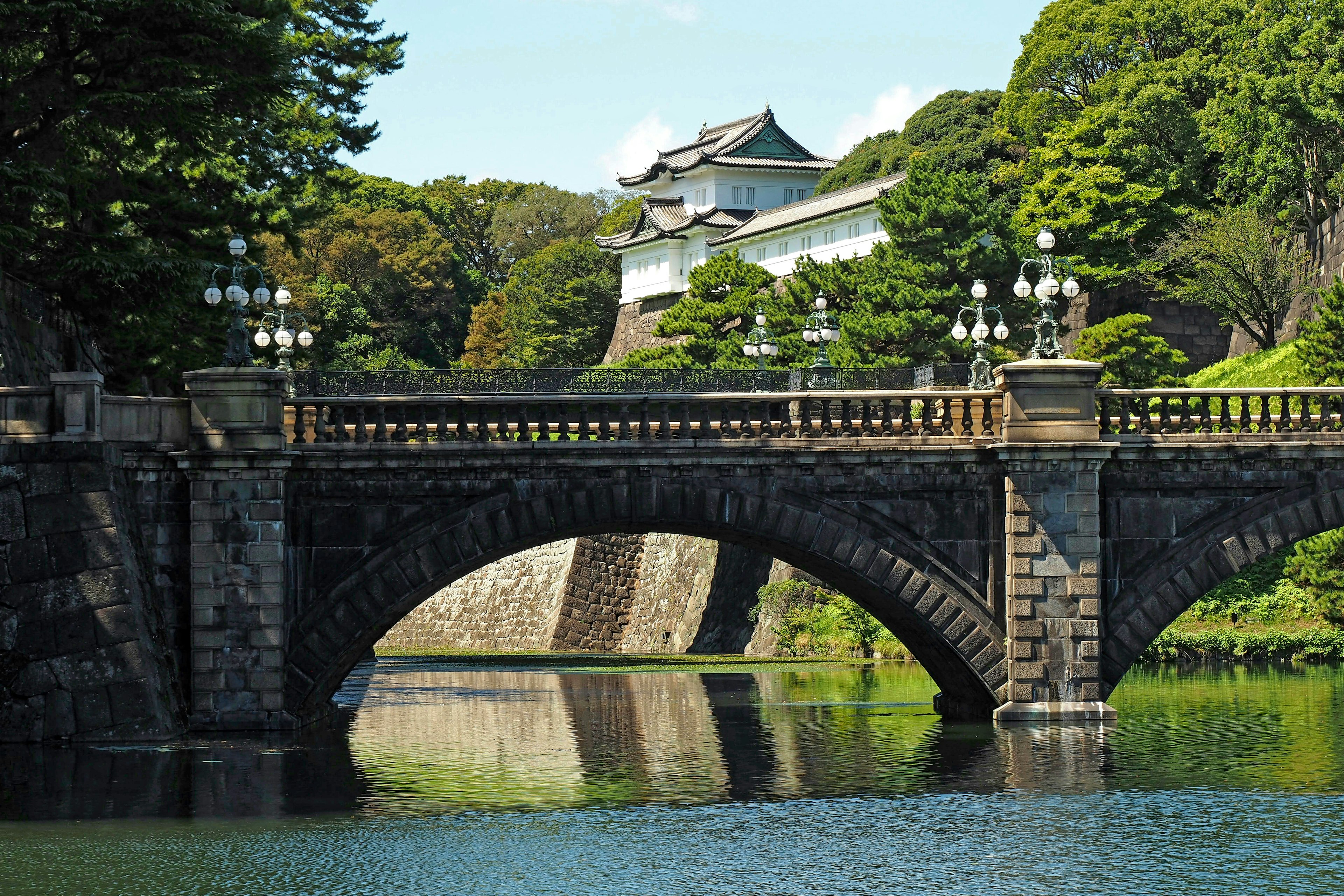 Puente de piedra del Palacio Imperial con vegetación exuberante y agua tranquila