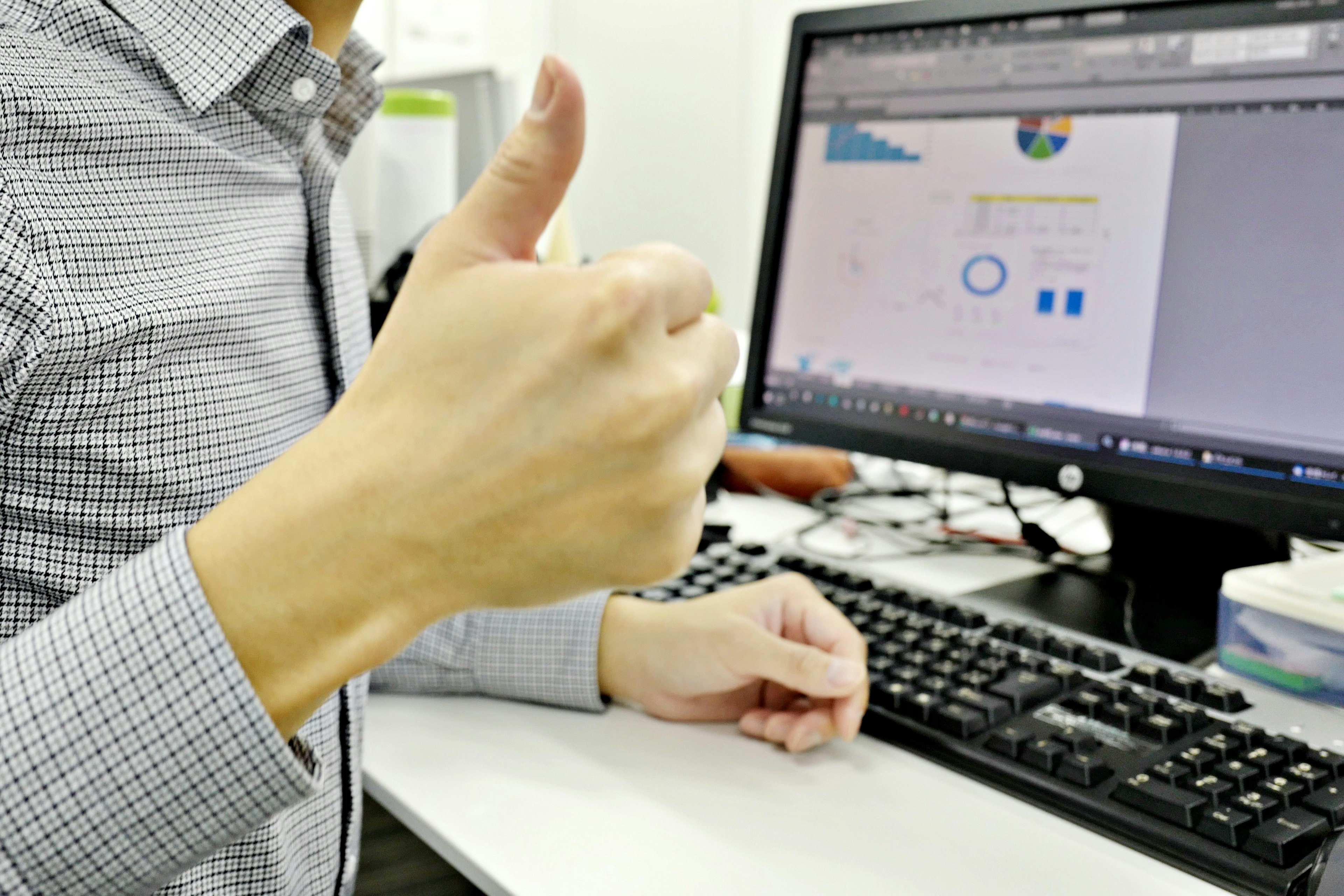 Hombre de negocios dando un pulgar hacia arriba frente a una computadora