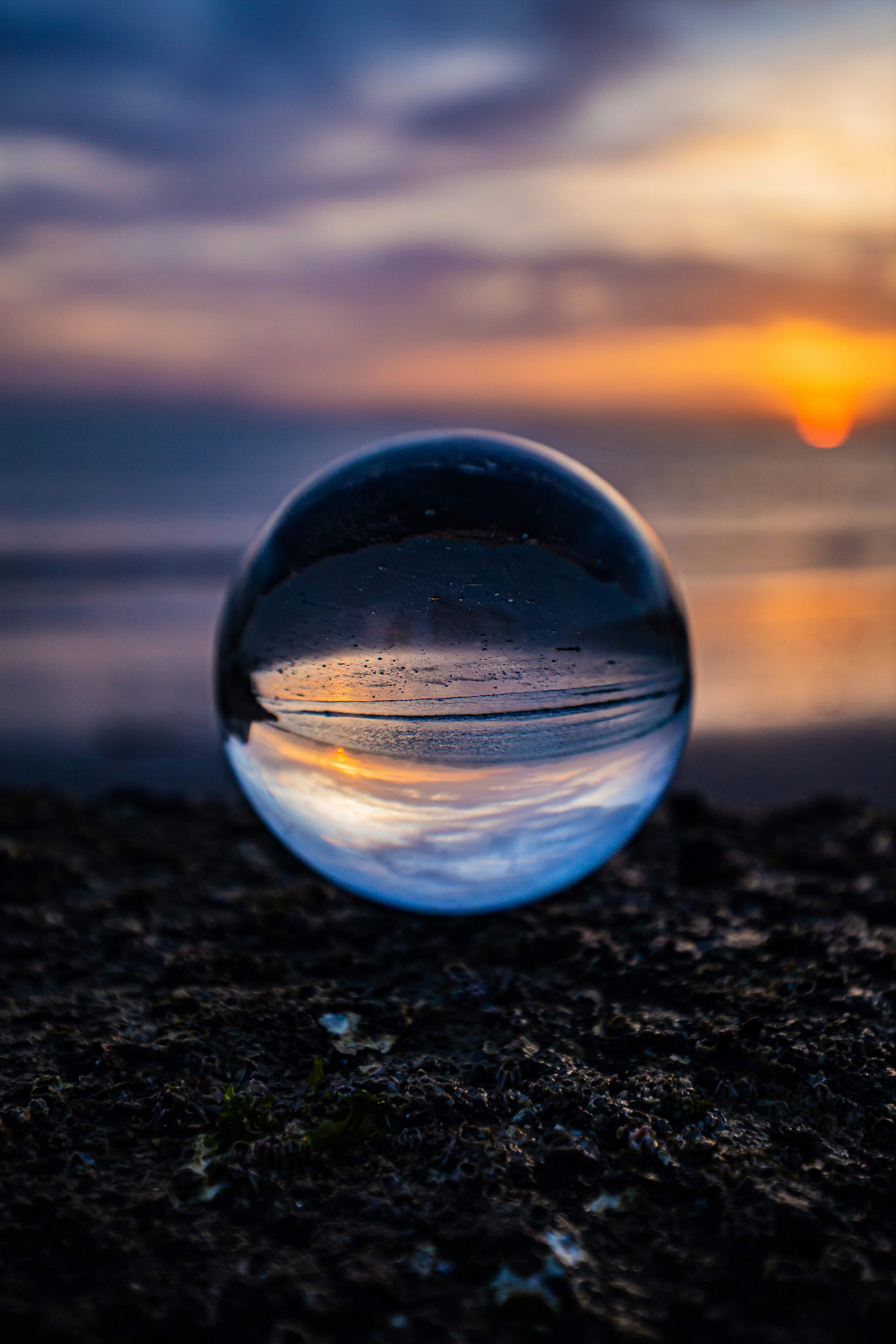 A clear glass sphere reflecting a sunset over the ocean