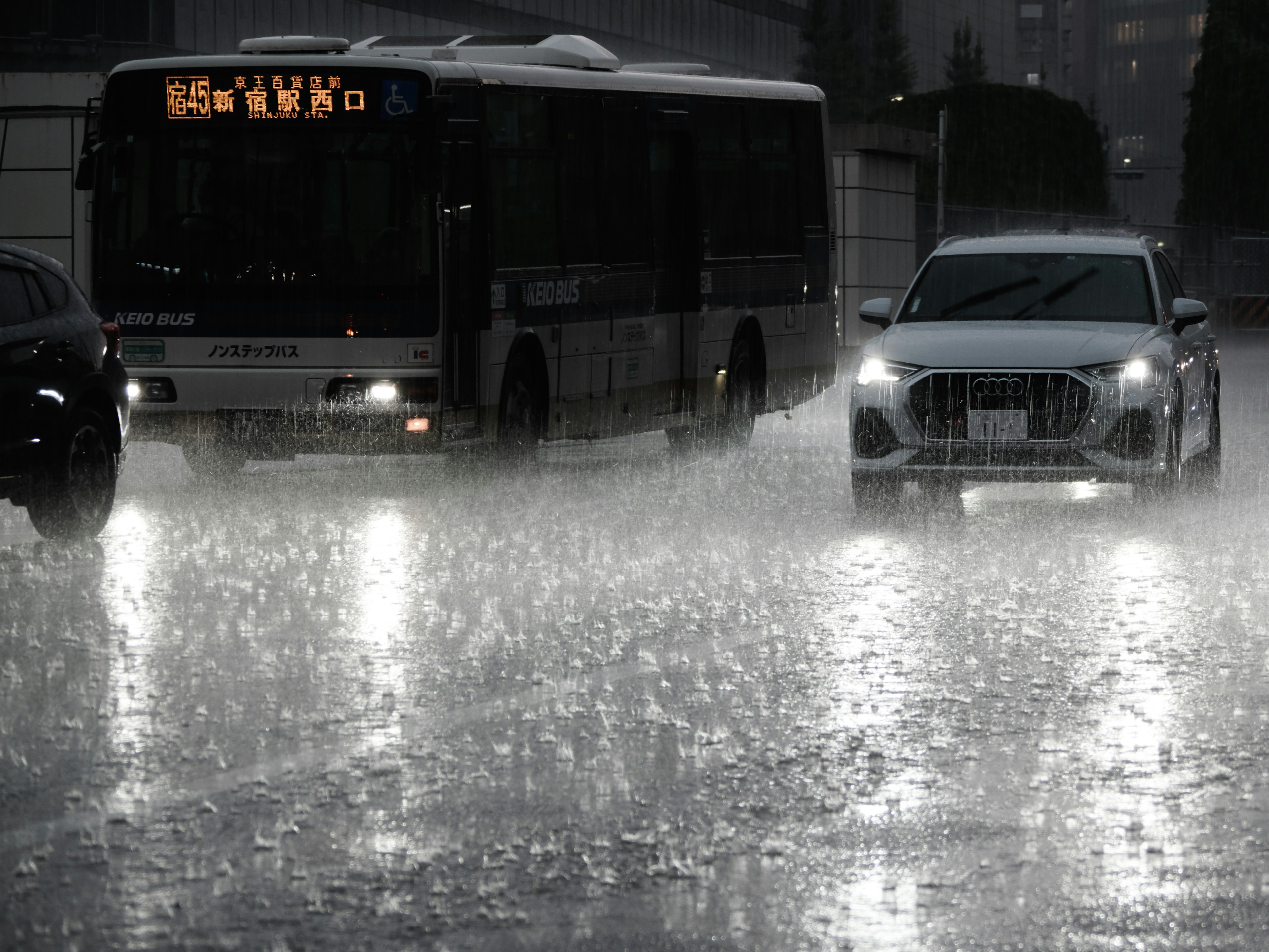 Szene eines Busses und eines Autos, die bei starkem Regen mit Pfützen fahren