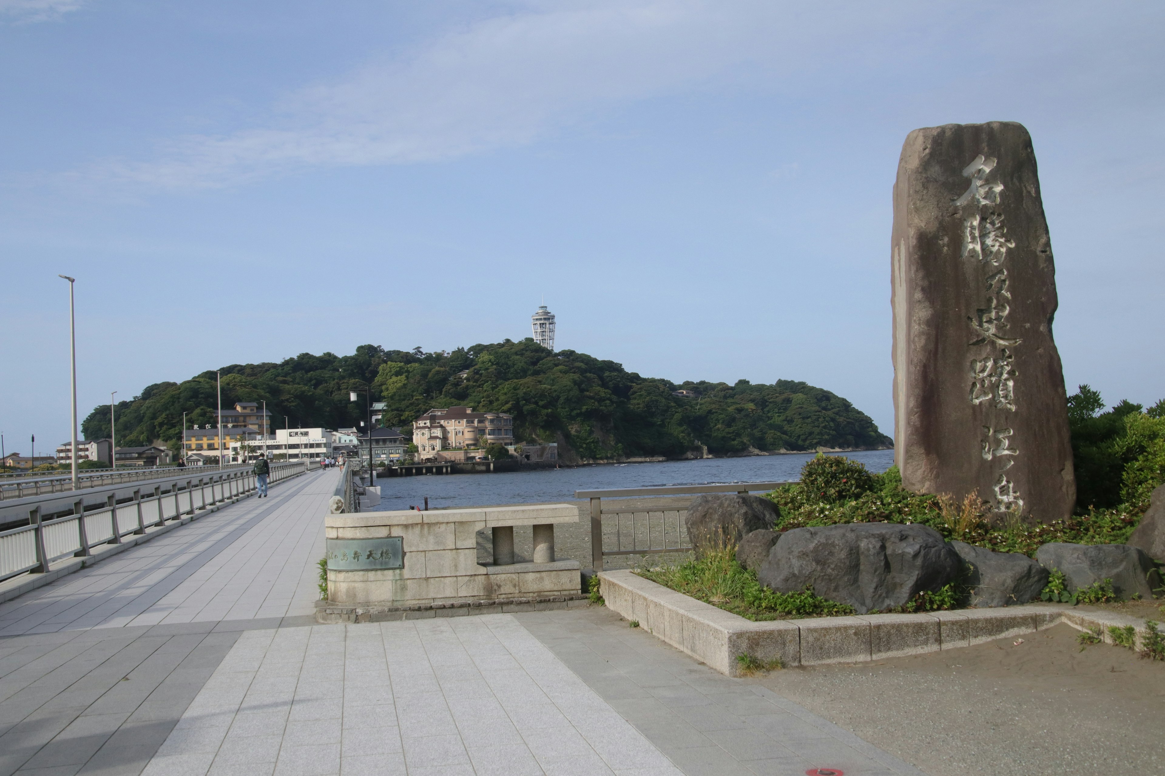 Vista costiera con un monumento e un'isola con faro in lontananza