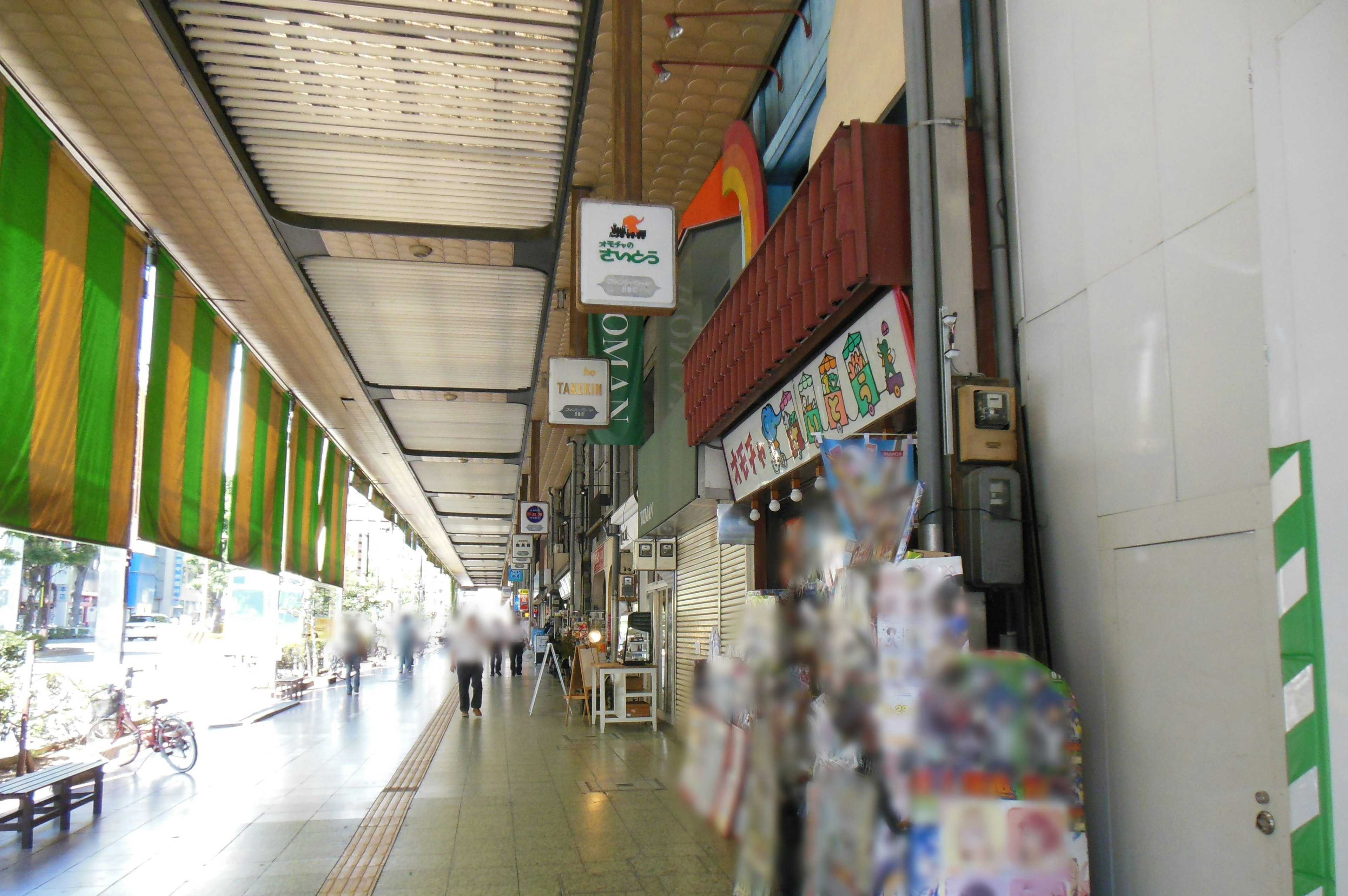 Vista interior de una calle comercial con cortinas coloridas y tiendas