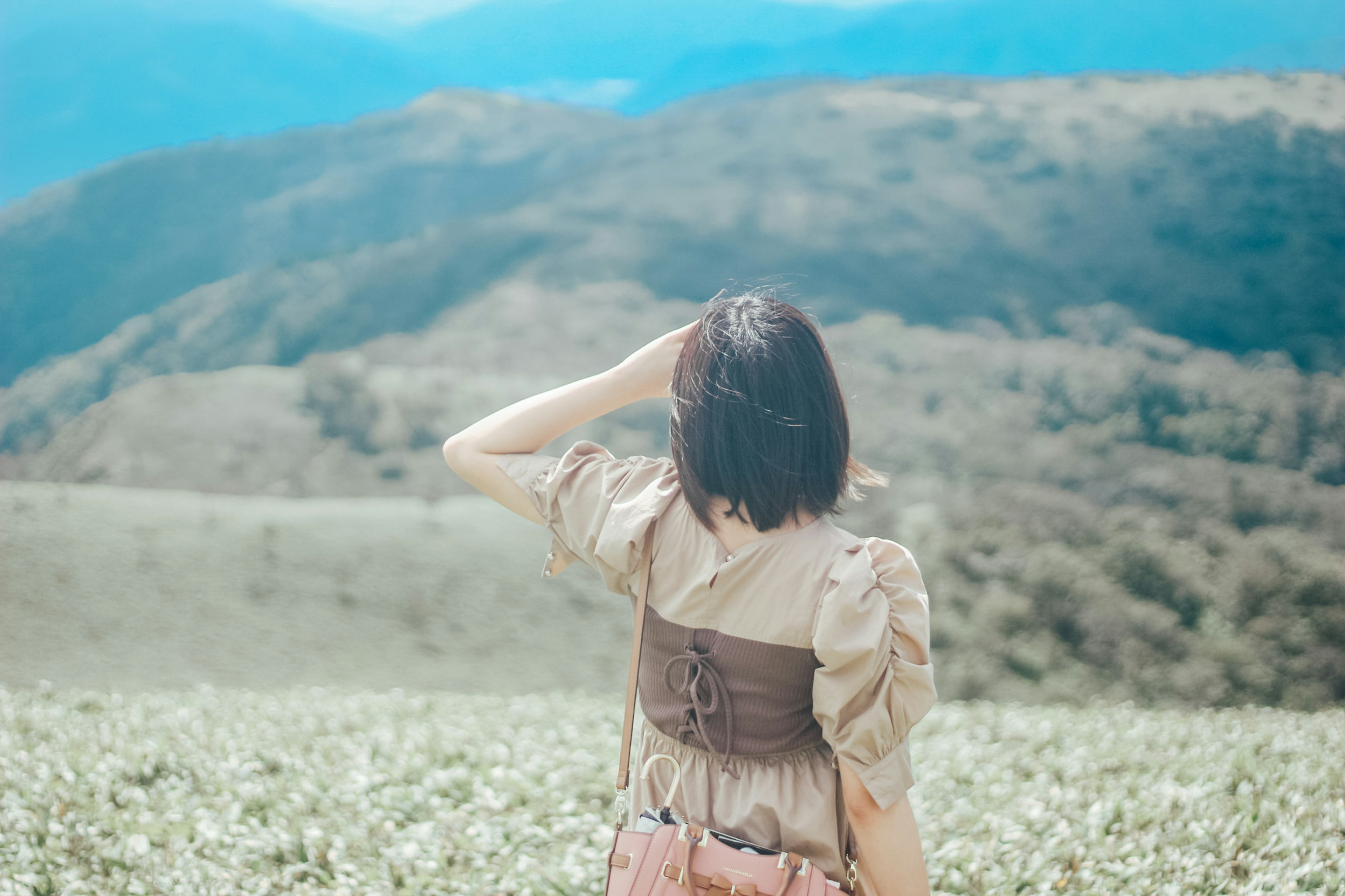 뒤에서 보는 여성이 녹색 언덕을 바라보는 풍경