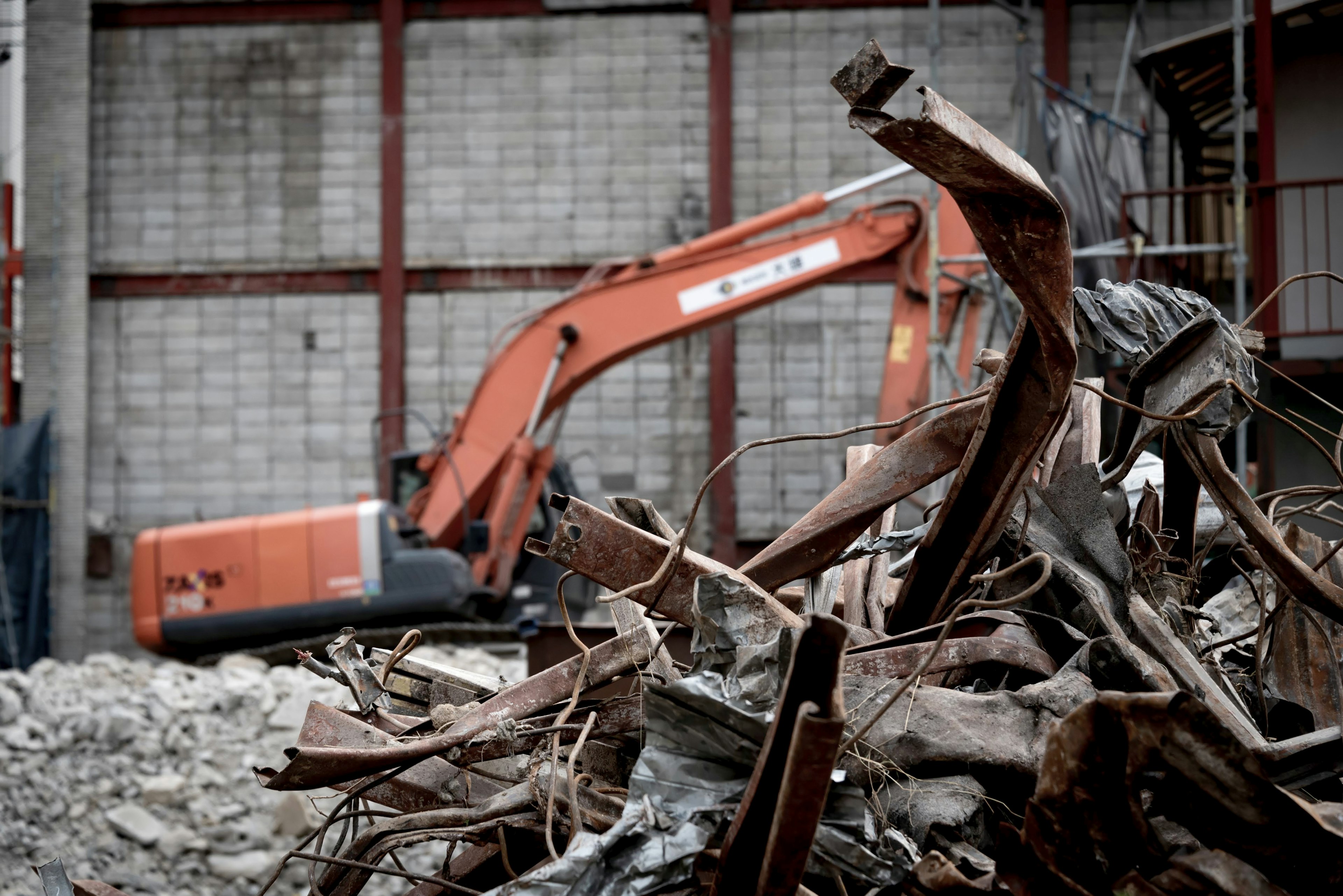 Excavator at a demolition site with metal debris