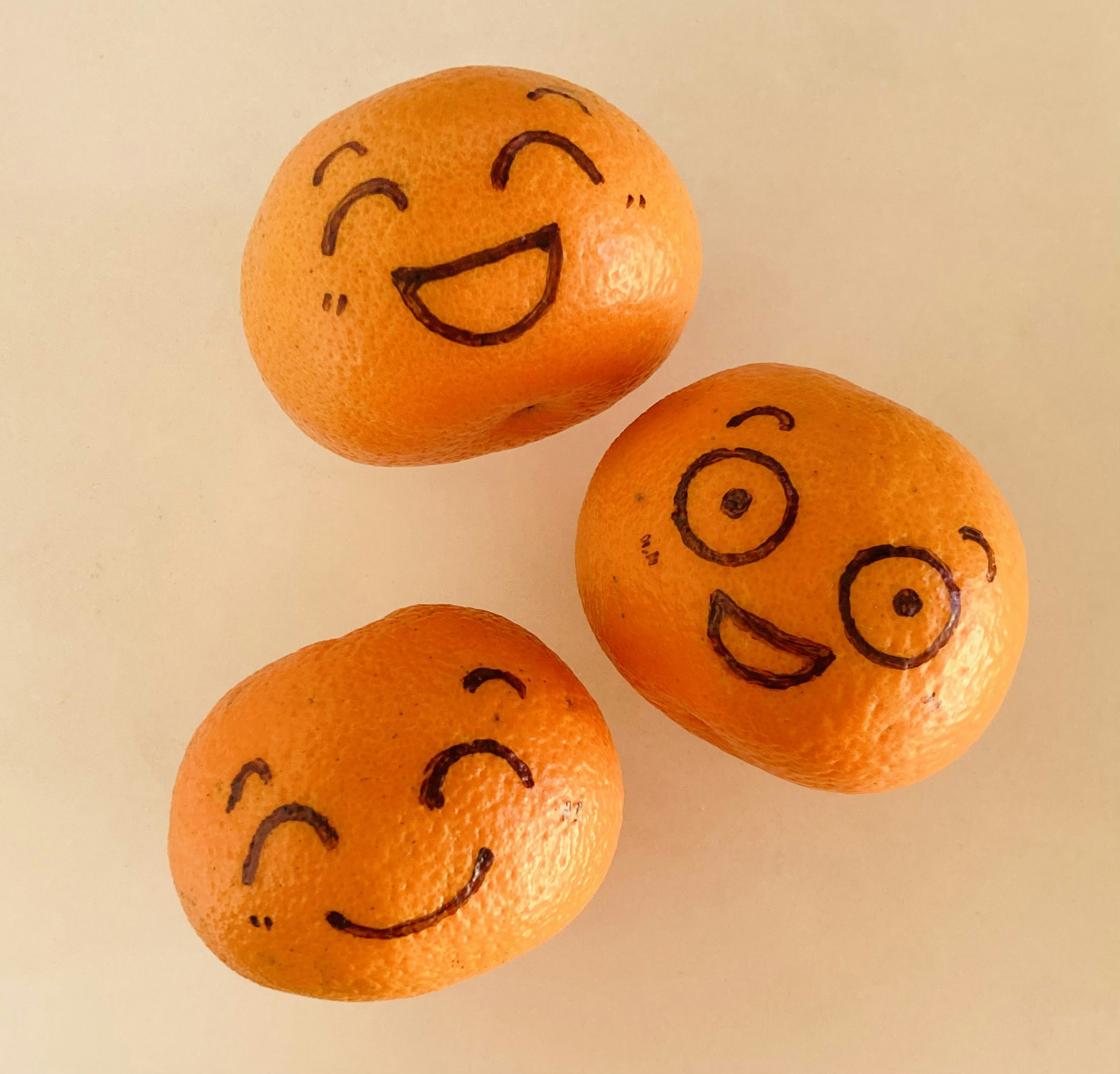 Three oranges with drawn smiling faces