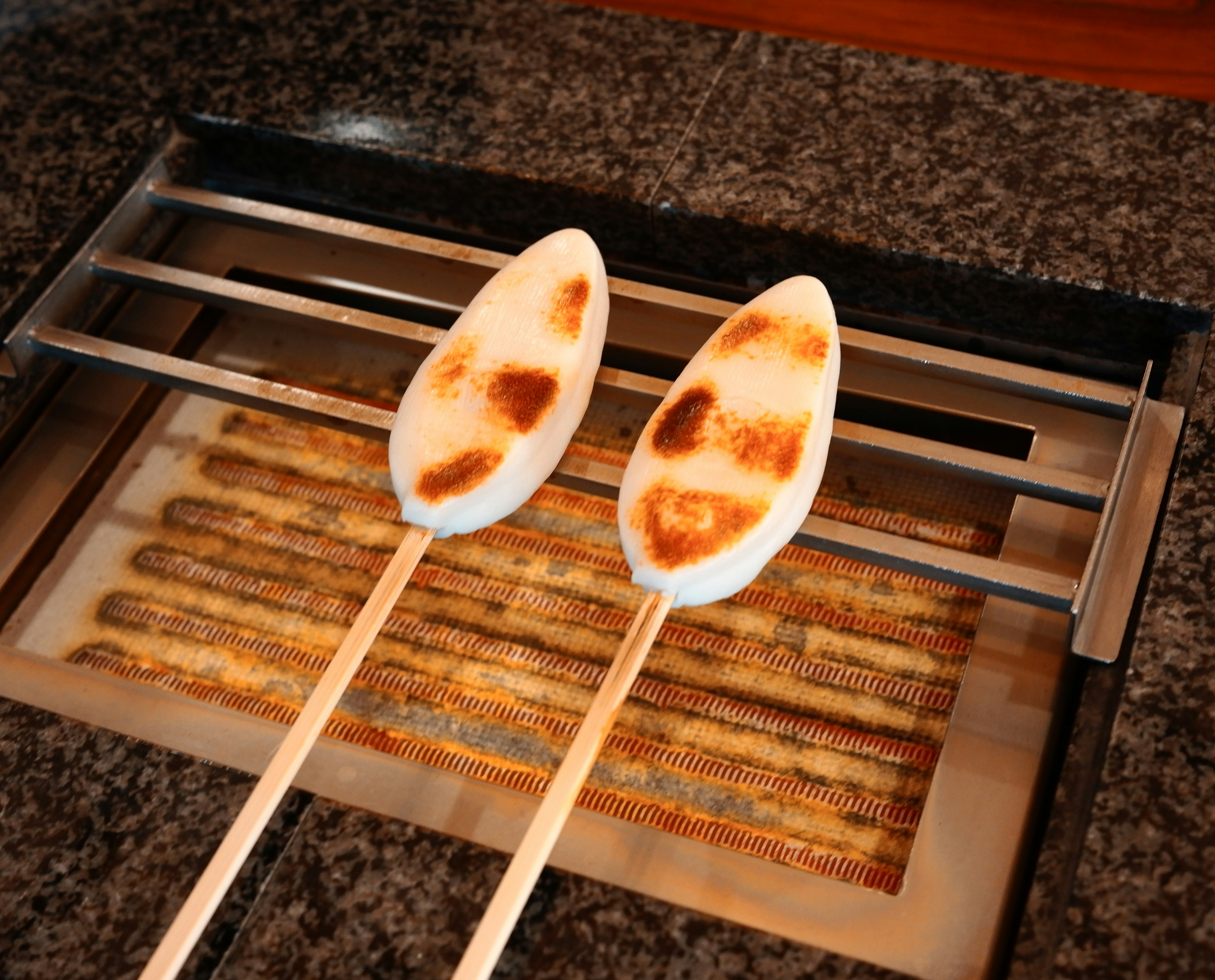 Pain blanc grillé sur des brochettes cuisant sur un élément chauffant