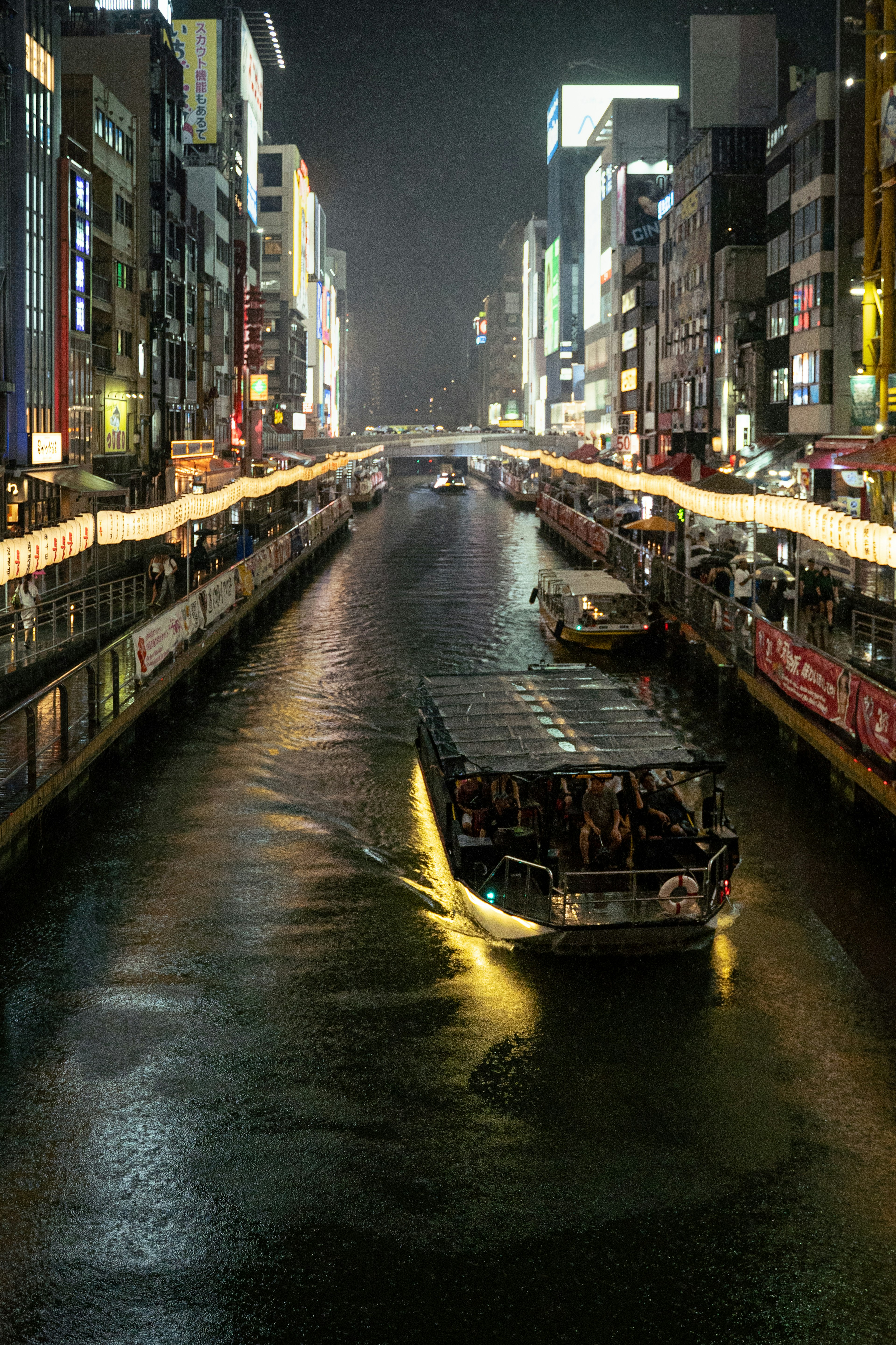 夜の川を行く観光船と明るい街灯