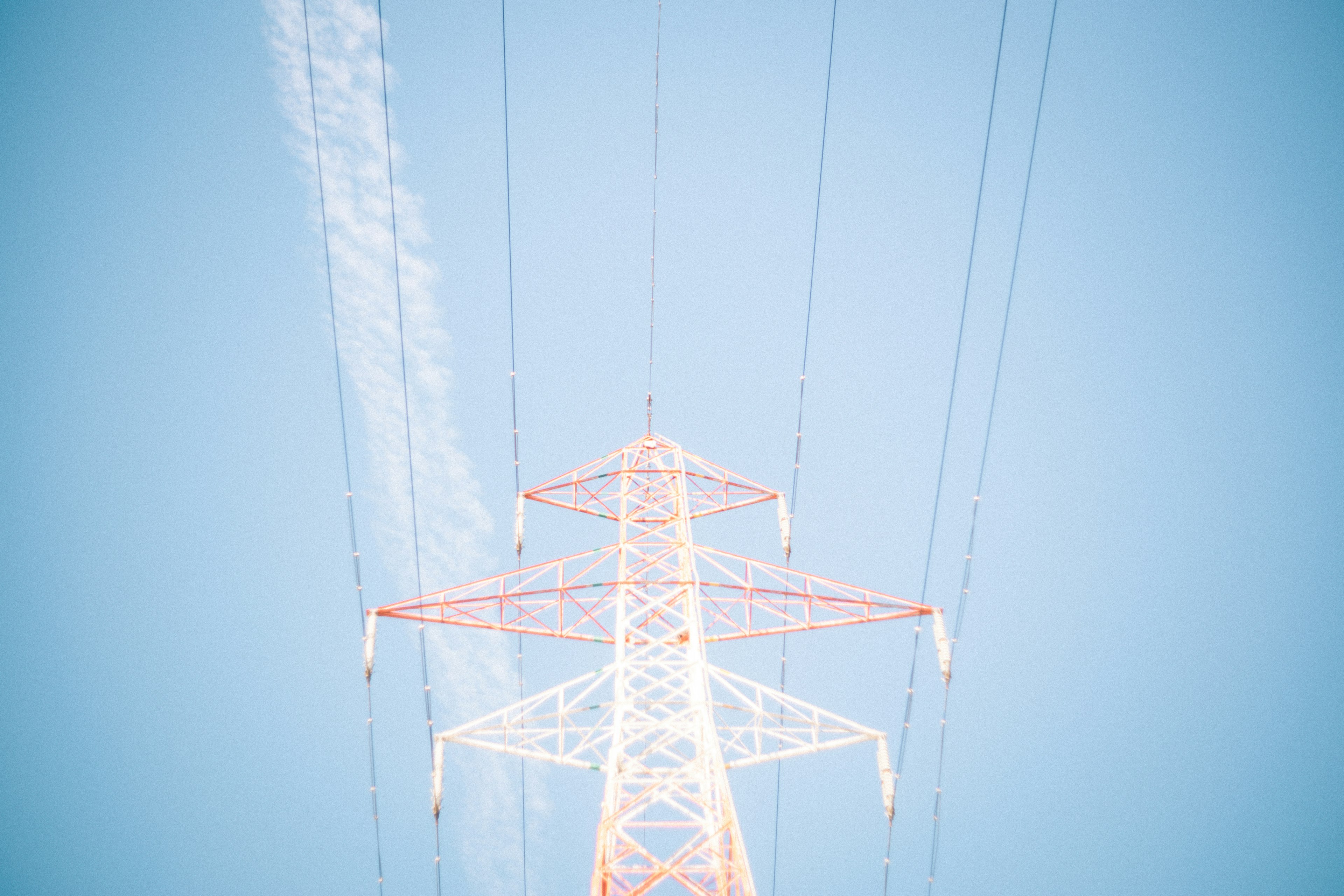 Foto di un palo della luce e linee elettriche contro un cielo blu