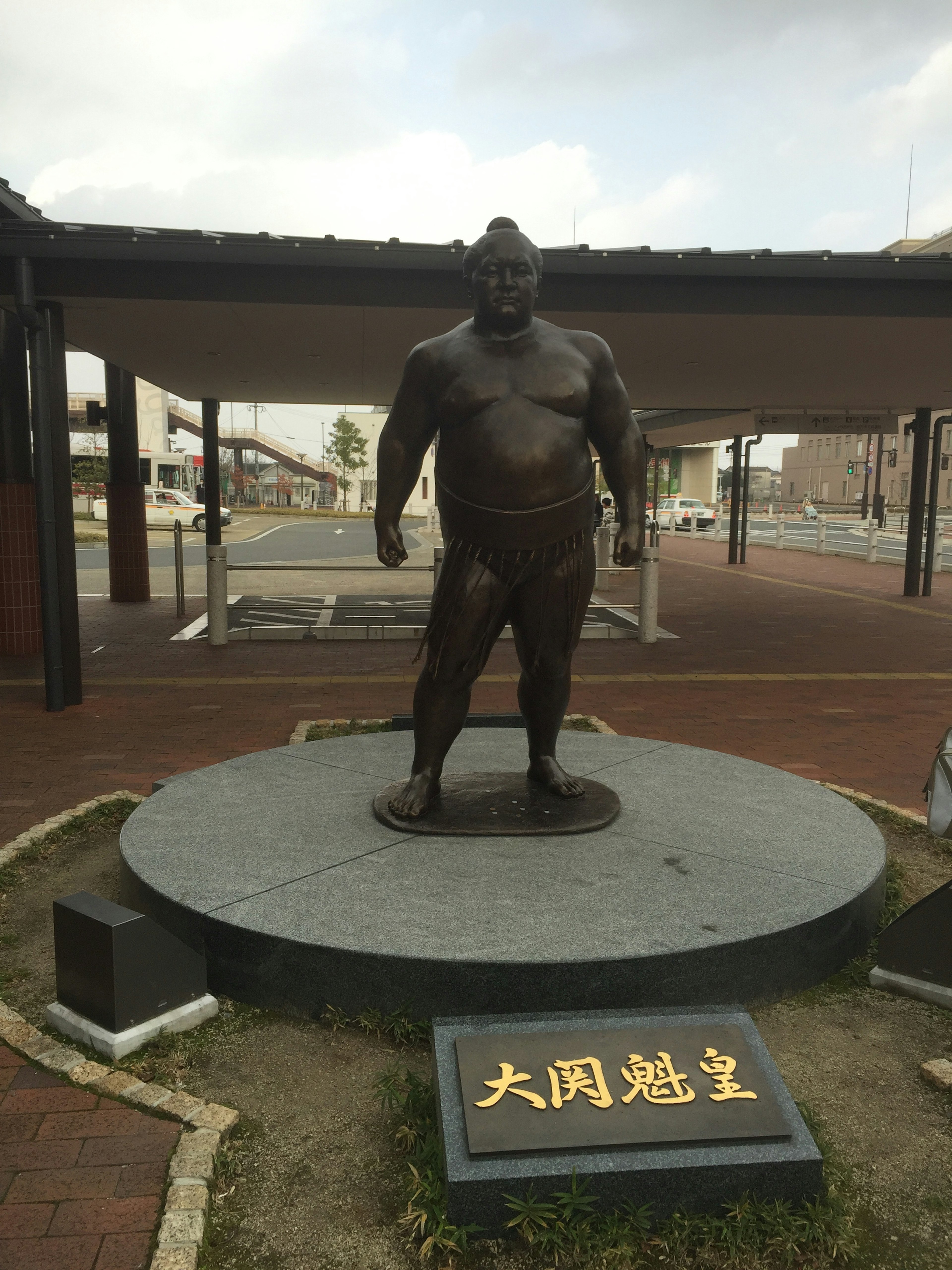 Statue of a sumo wrestler standing on a circular platform