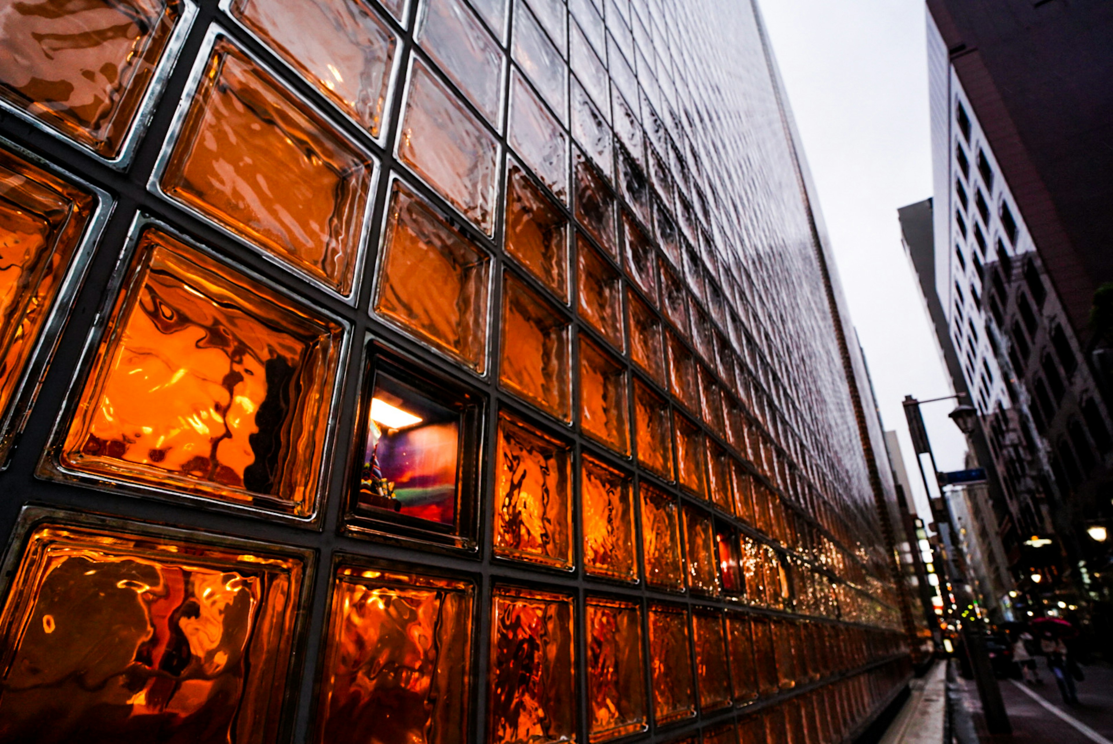 Urban scene featuring a wall of glass blocks with warm amber tones