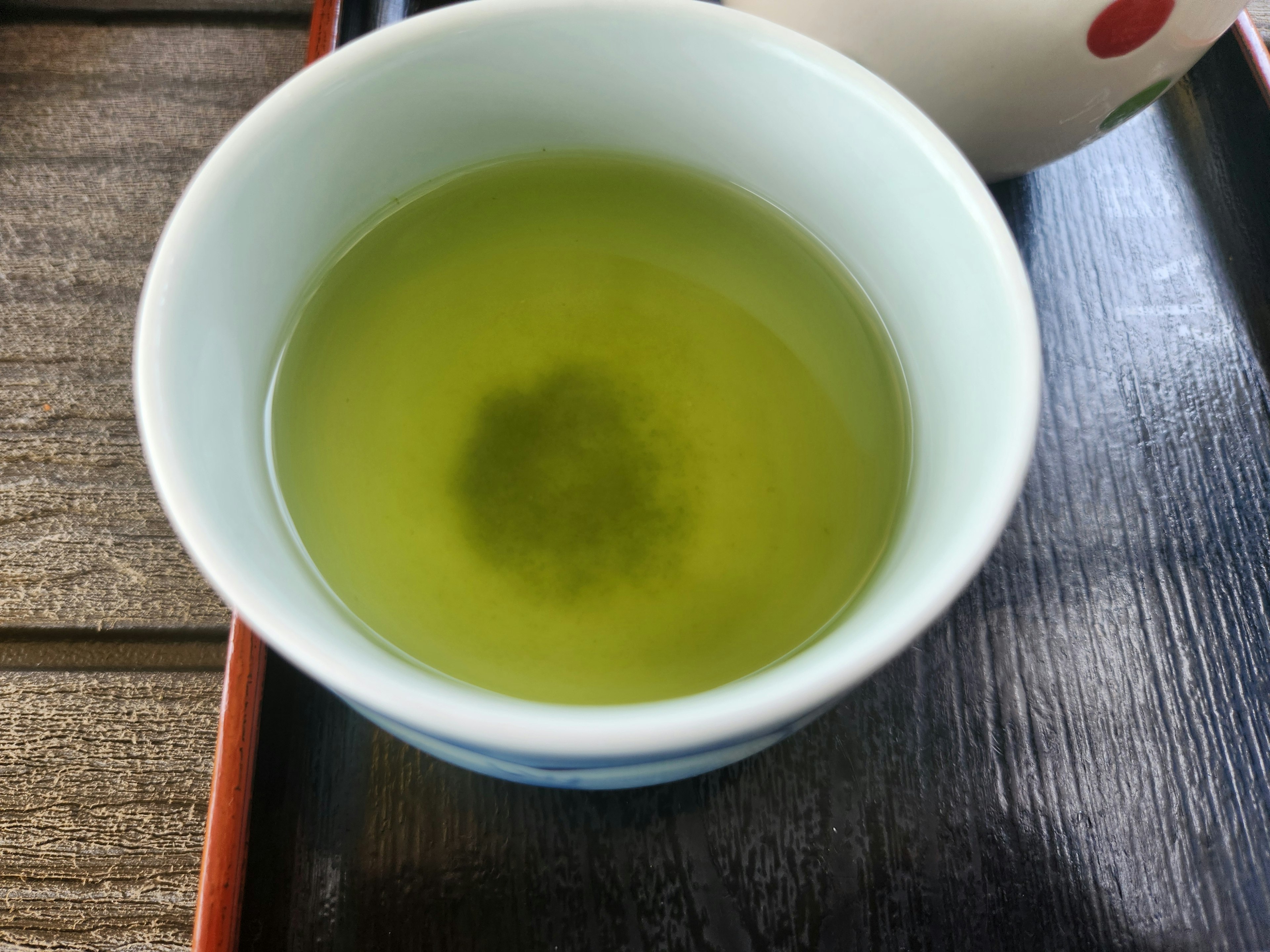 Une tasse de thé vert posée sur une table en bois