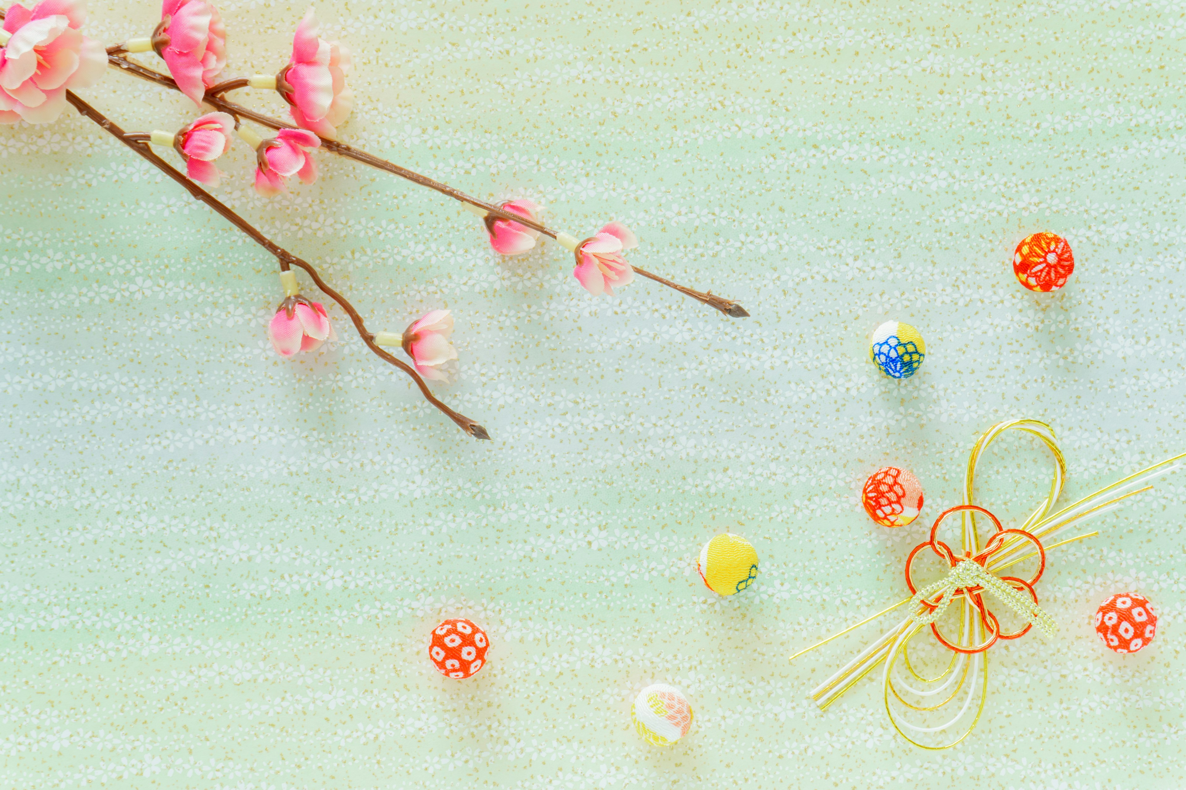 Delicate green background with pink flowers and colorful beads scattered