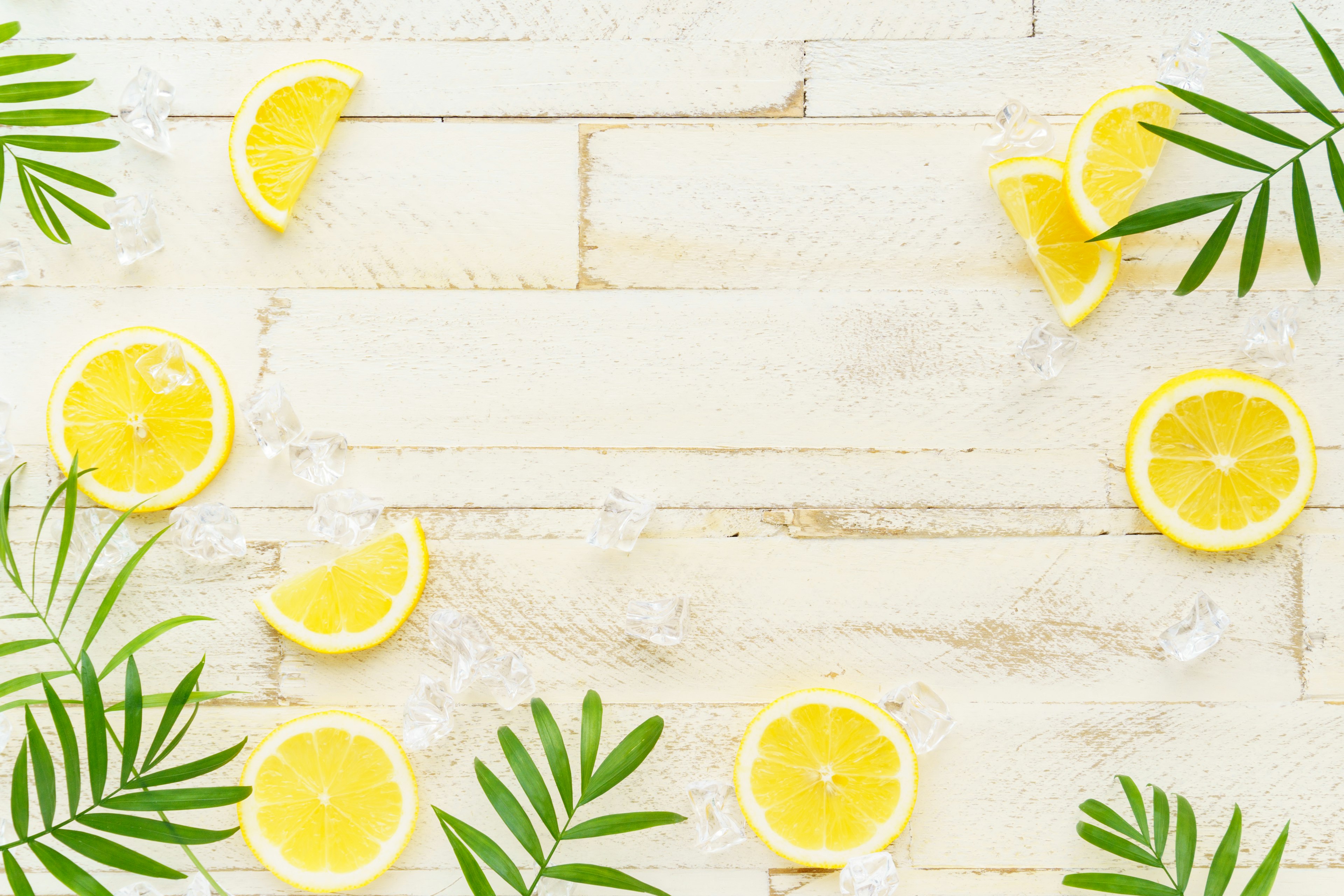 Des tranches de citron et des feuilles vertes disposées sur une table en bois blanc