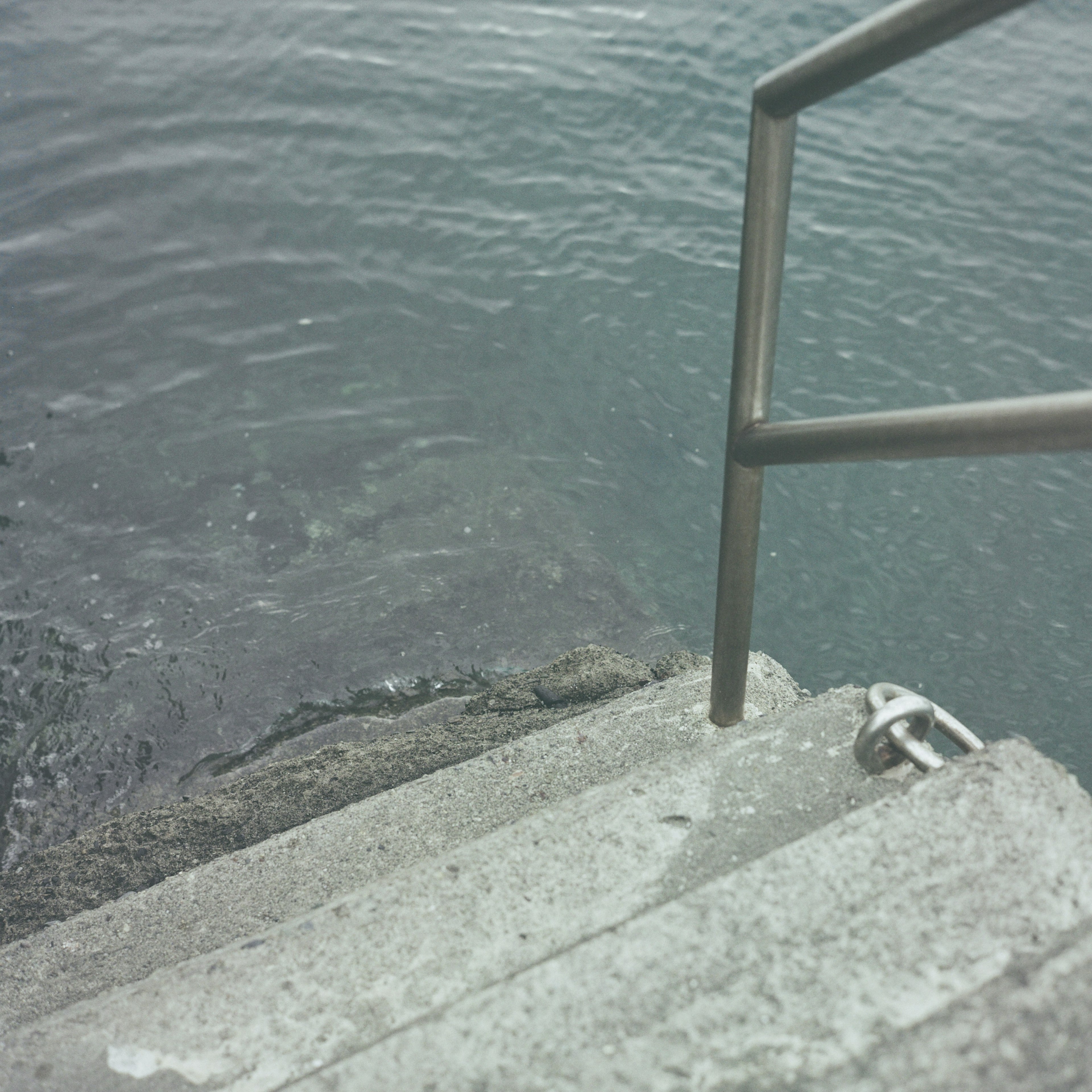 Concrete steps leading to water with a metal railing