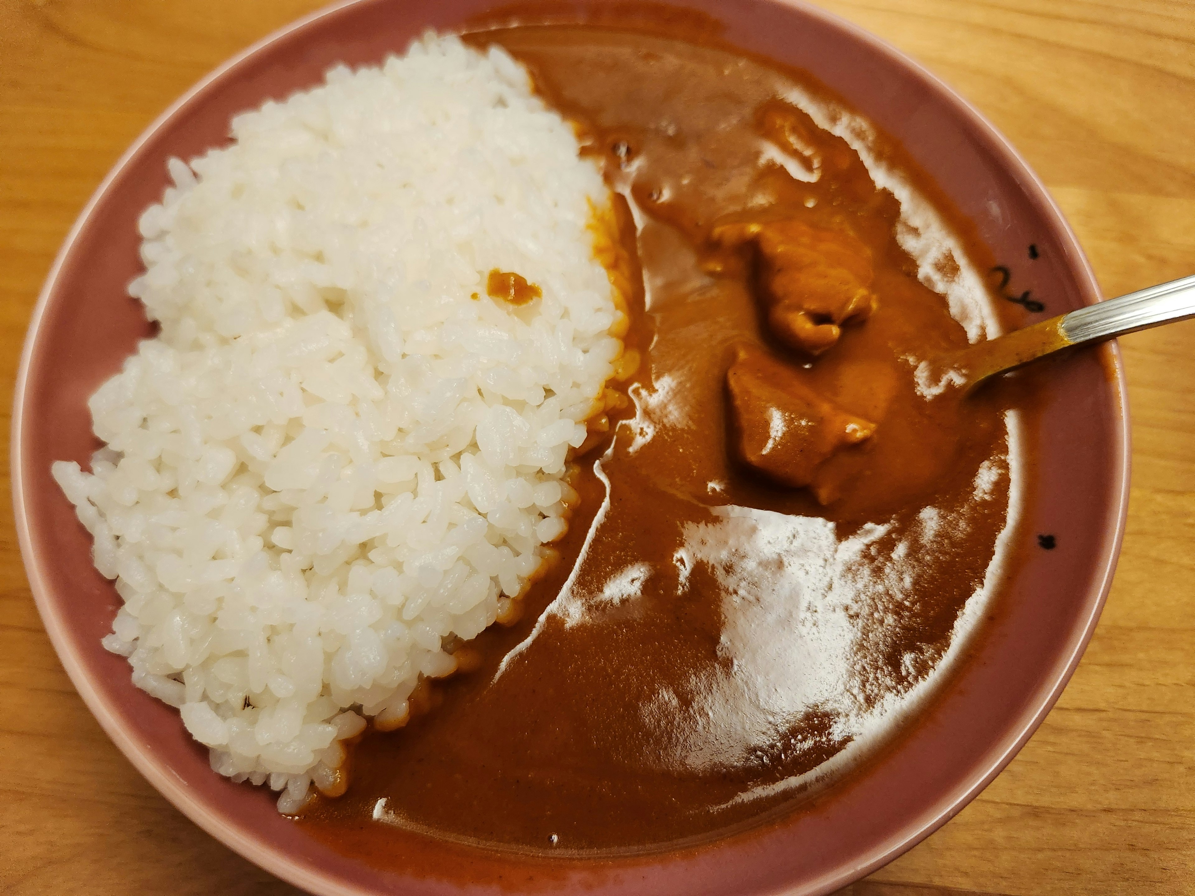 Une assiette avec du curry et du riz avec une sauce curry brune et du riz blanc