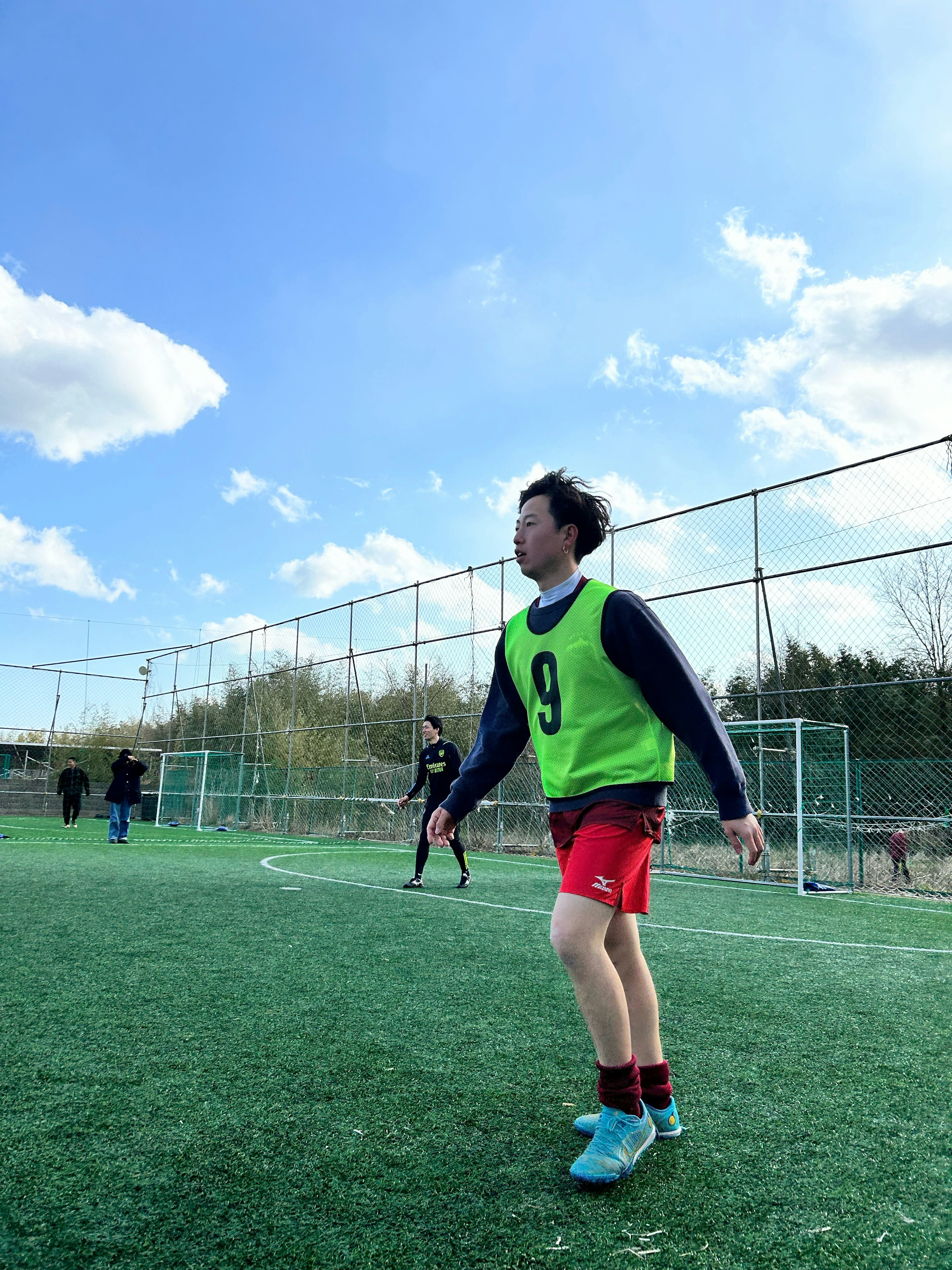 Soccer player wearing a green bib practicing on a field