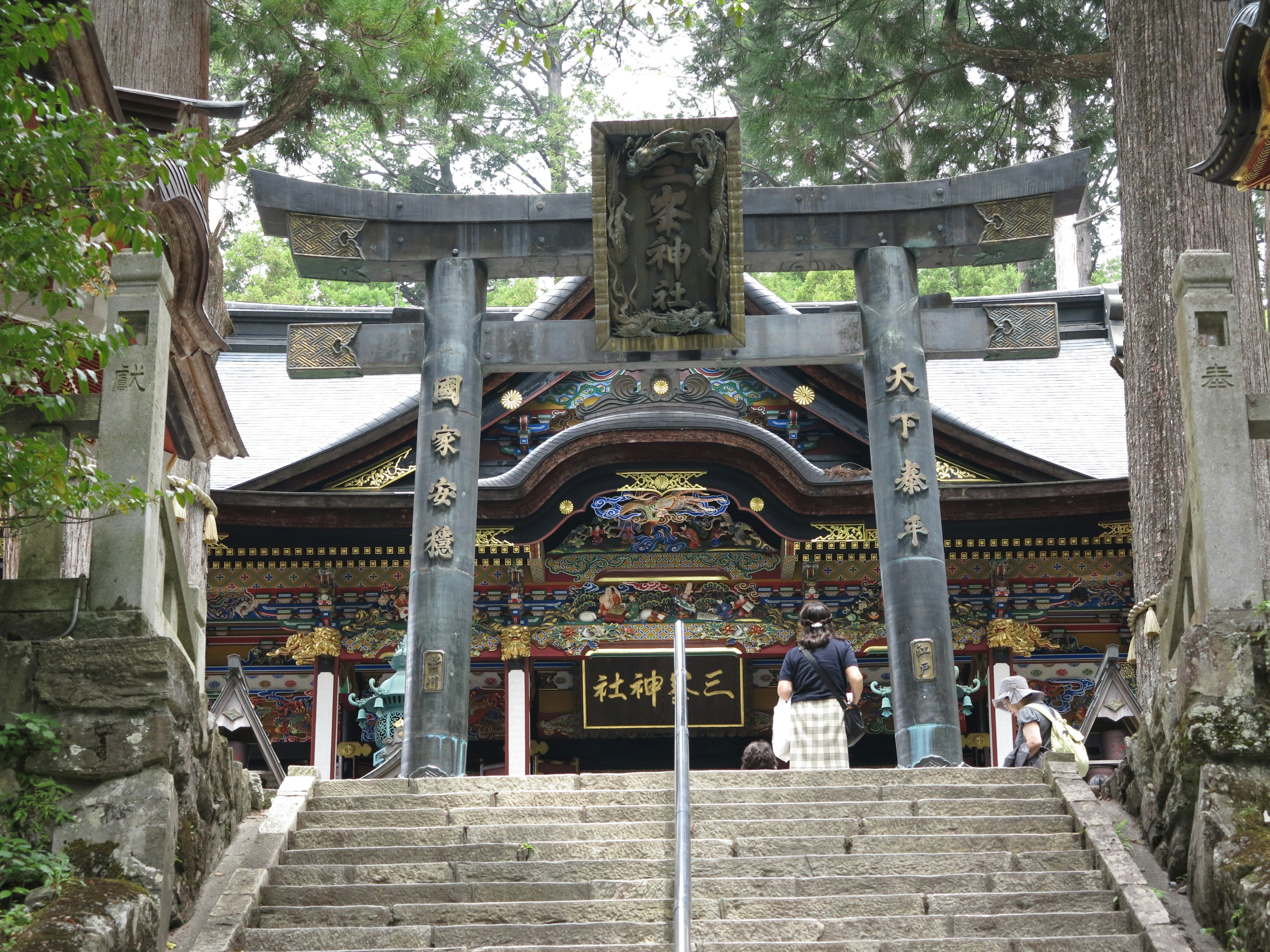 美しい神社の鳥居と階段の景色、周囲の緑の木々が印象的