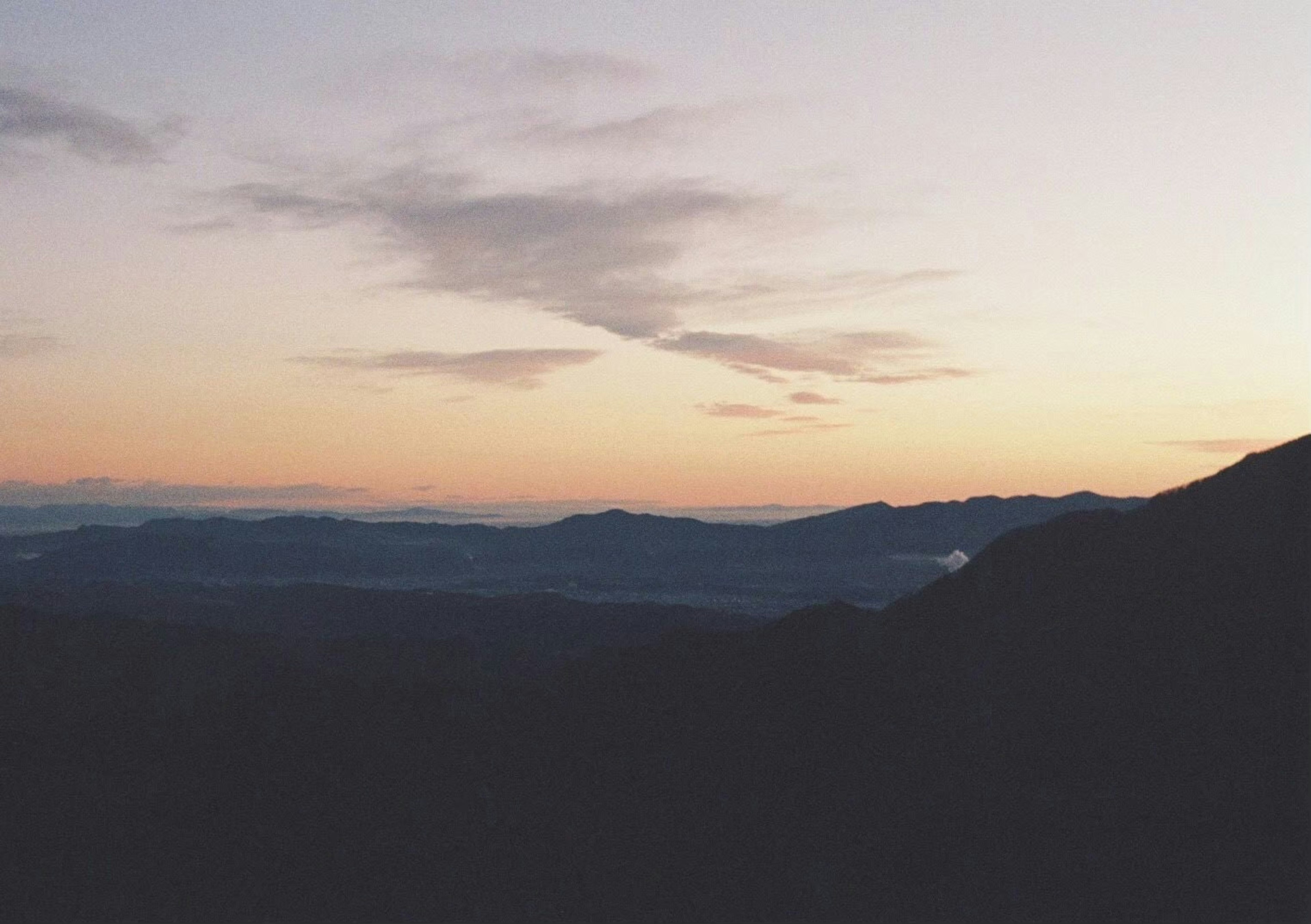 Pemandangan pegunungan saat senja dengan awan lembut