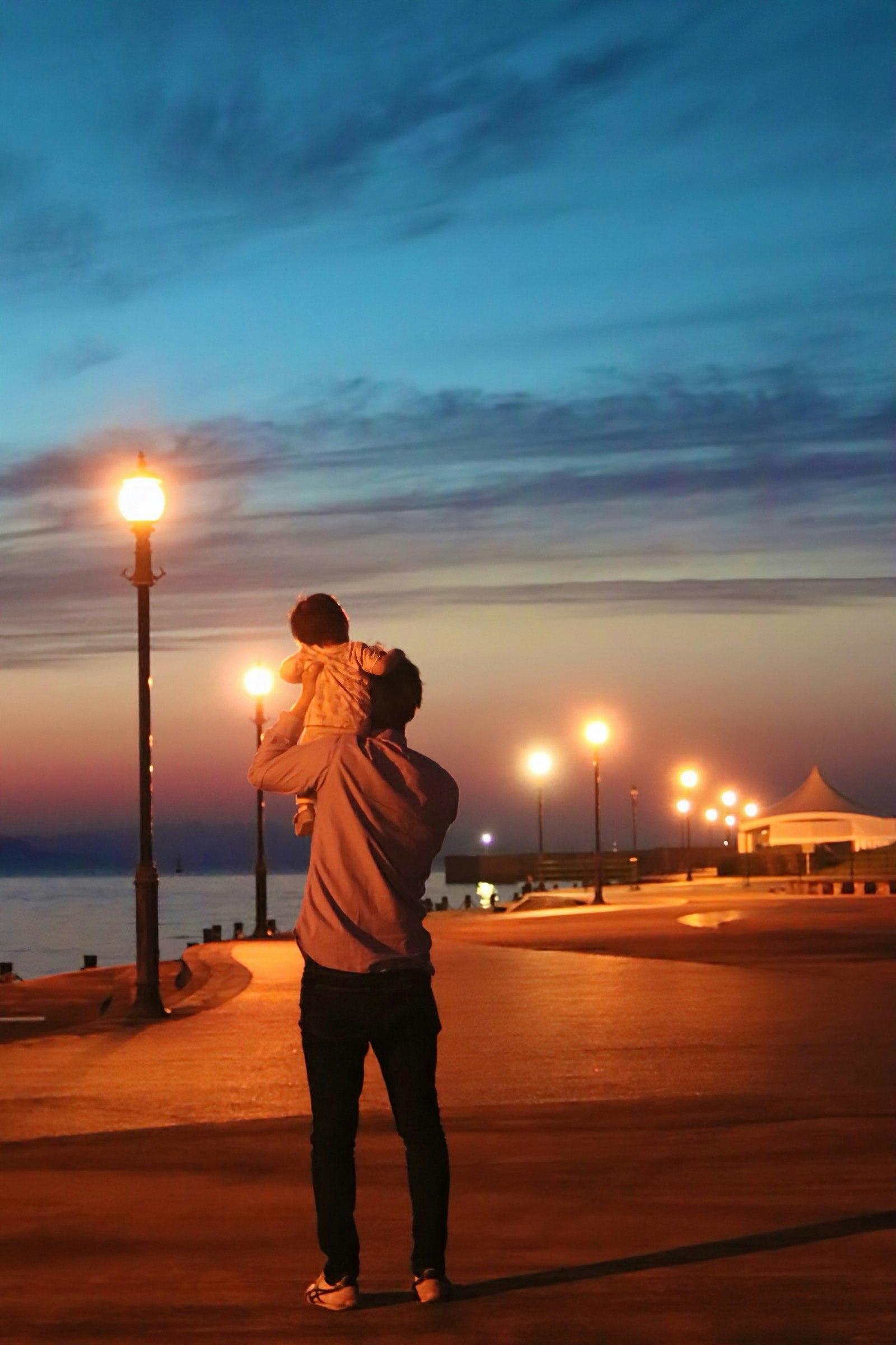 Silhouette of a father holding a child at dusk by the seaside
